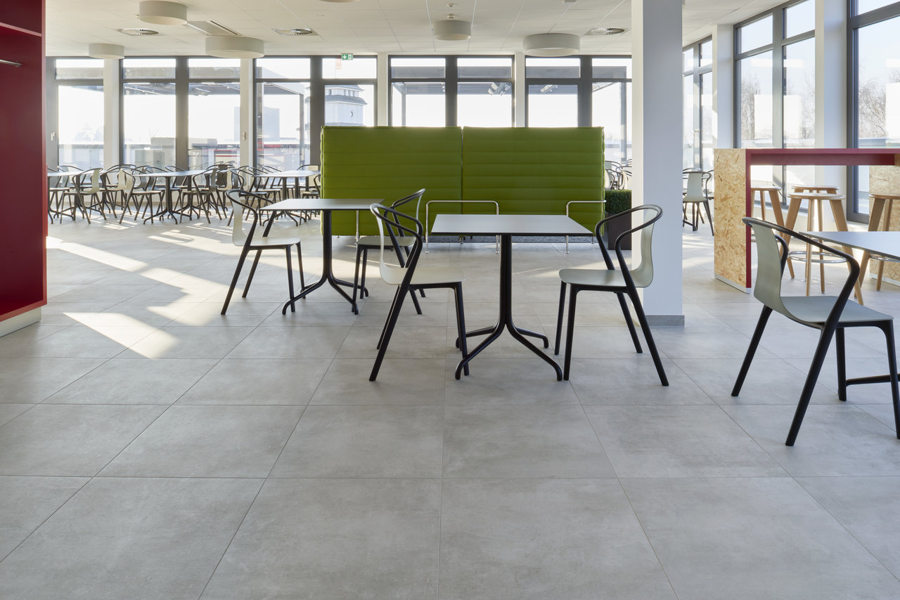 Modern, large-format grey tiles in a bright, open office area.