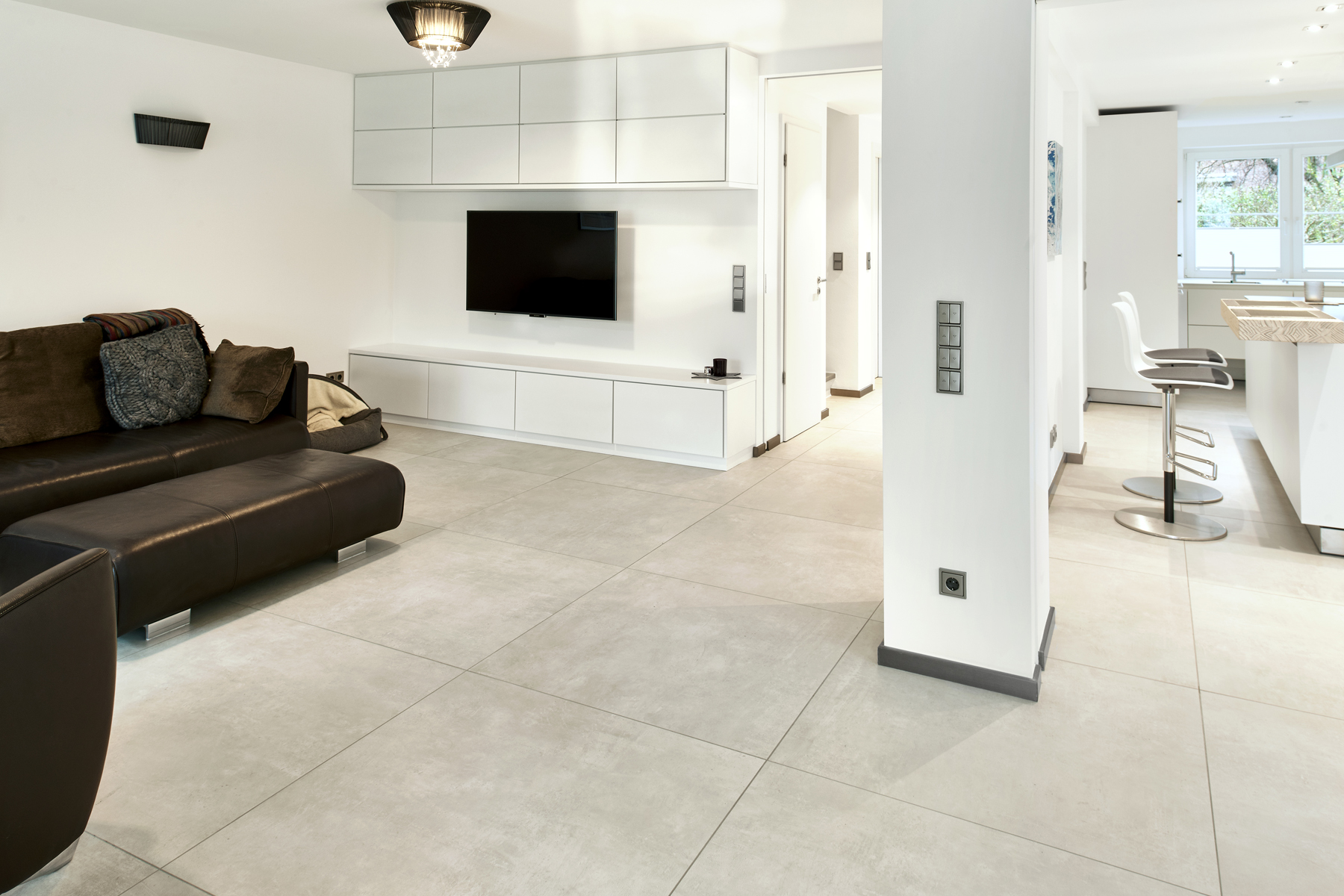 Modern, light grey tiles in a spacious living area with an open-plan kitchen.