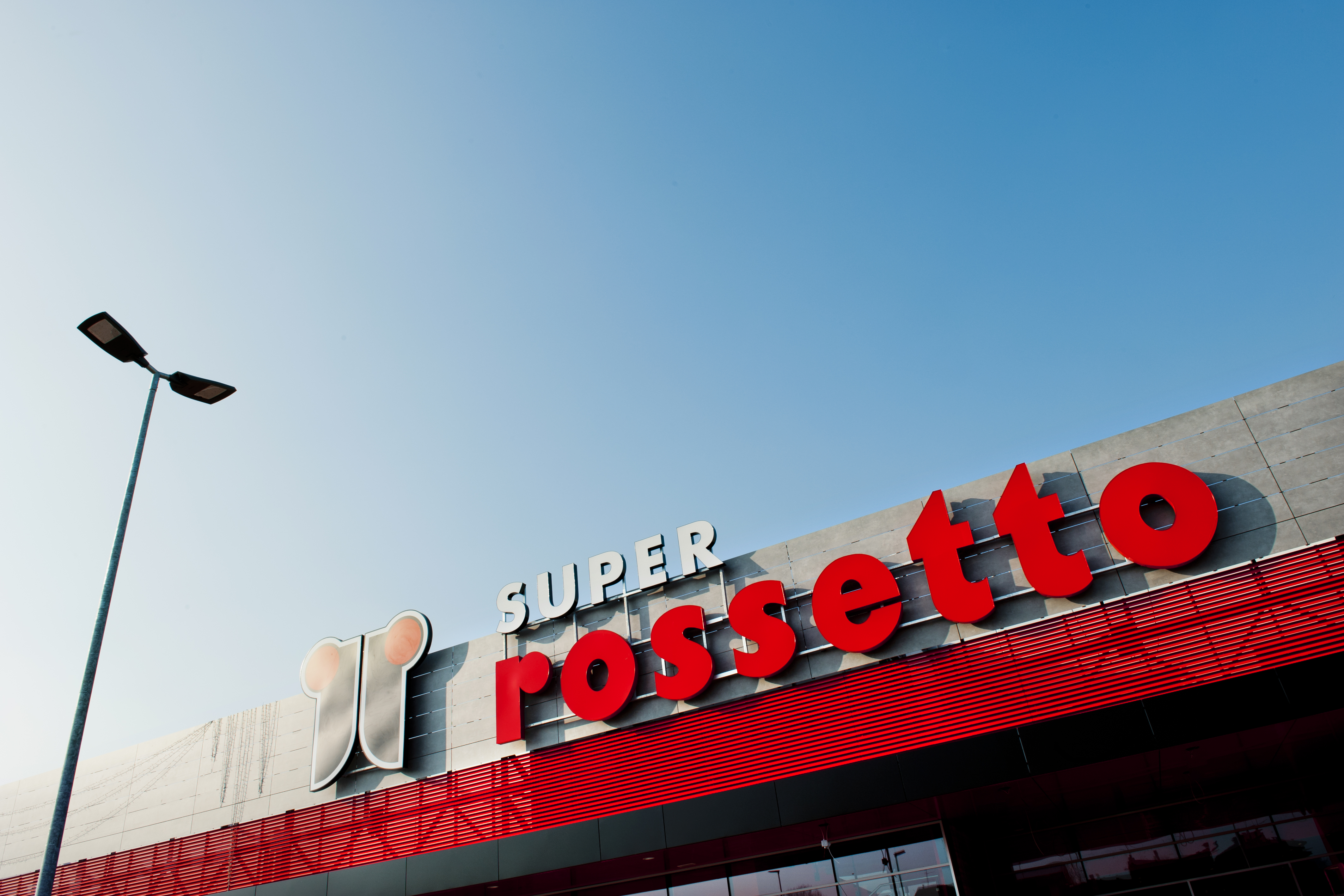 Building with red 'SUPER rossetto' lettering and a lantern against a blue sky.