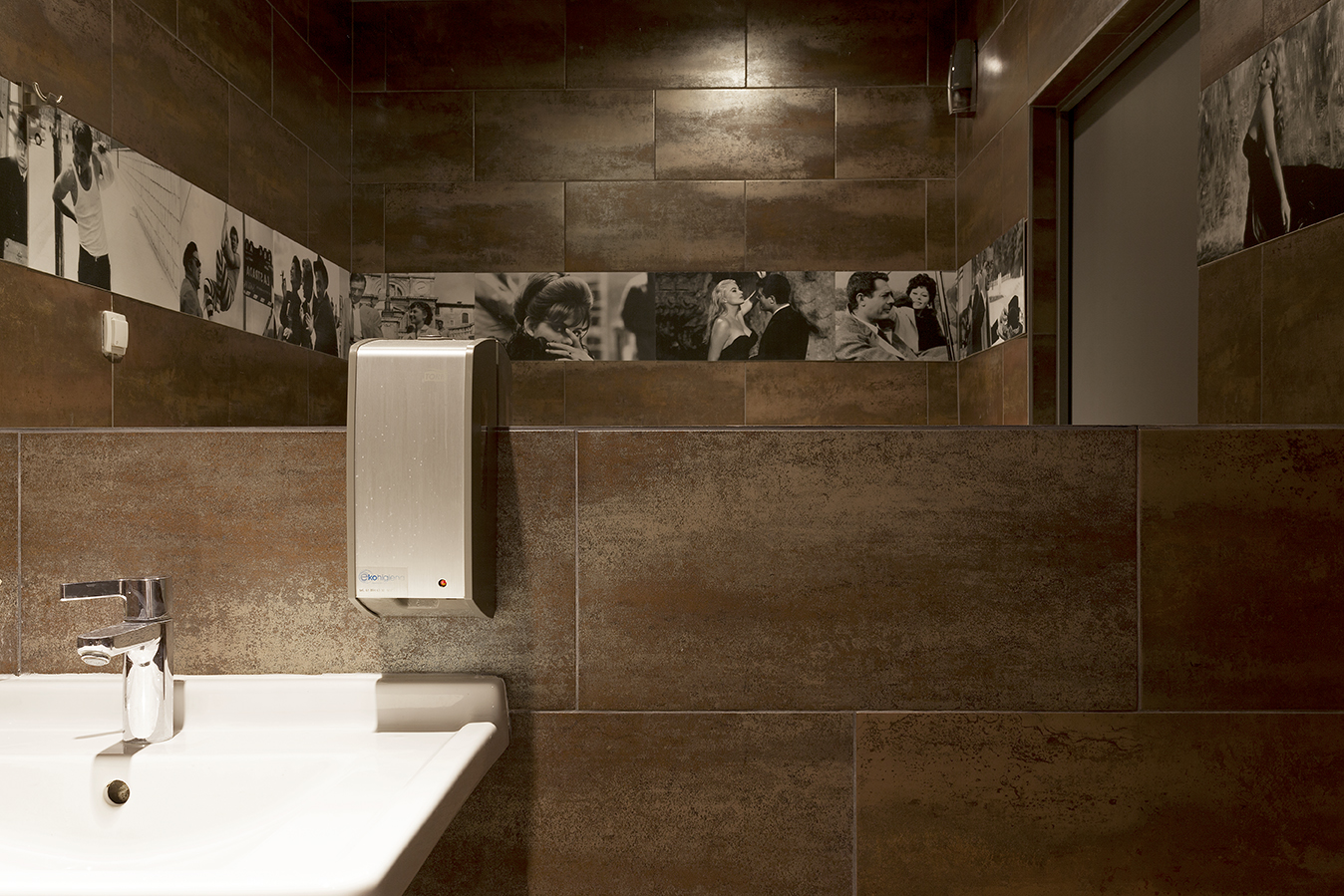 Elegant bathroom with dark brown porcelain tiles, washbasin, and soap dispenser.