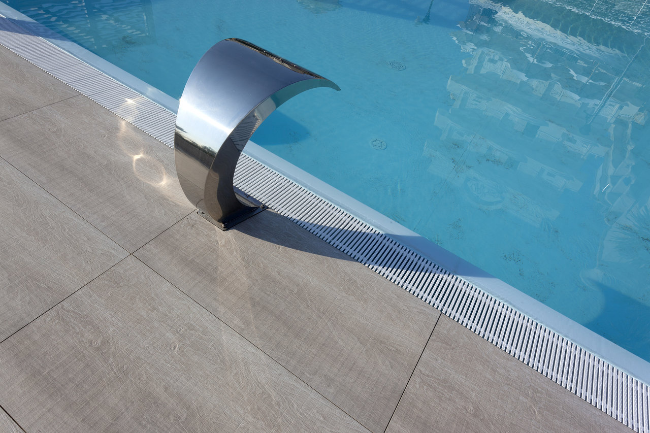Modern outdoor tiles by the pool with an elegant water spout.