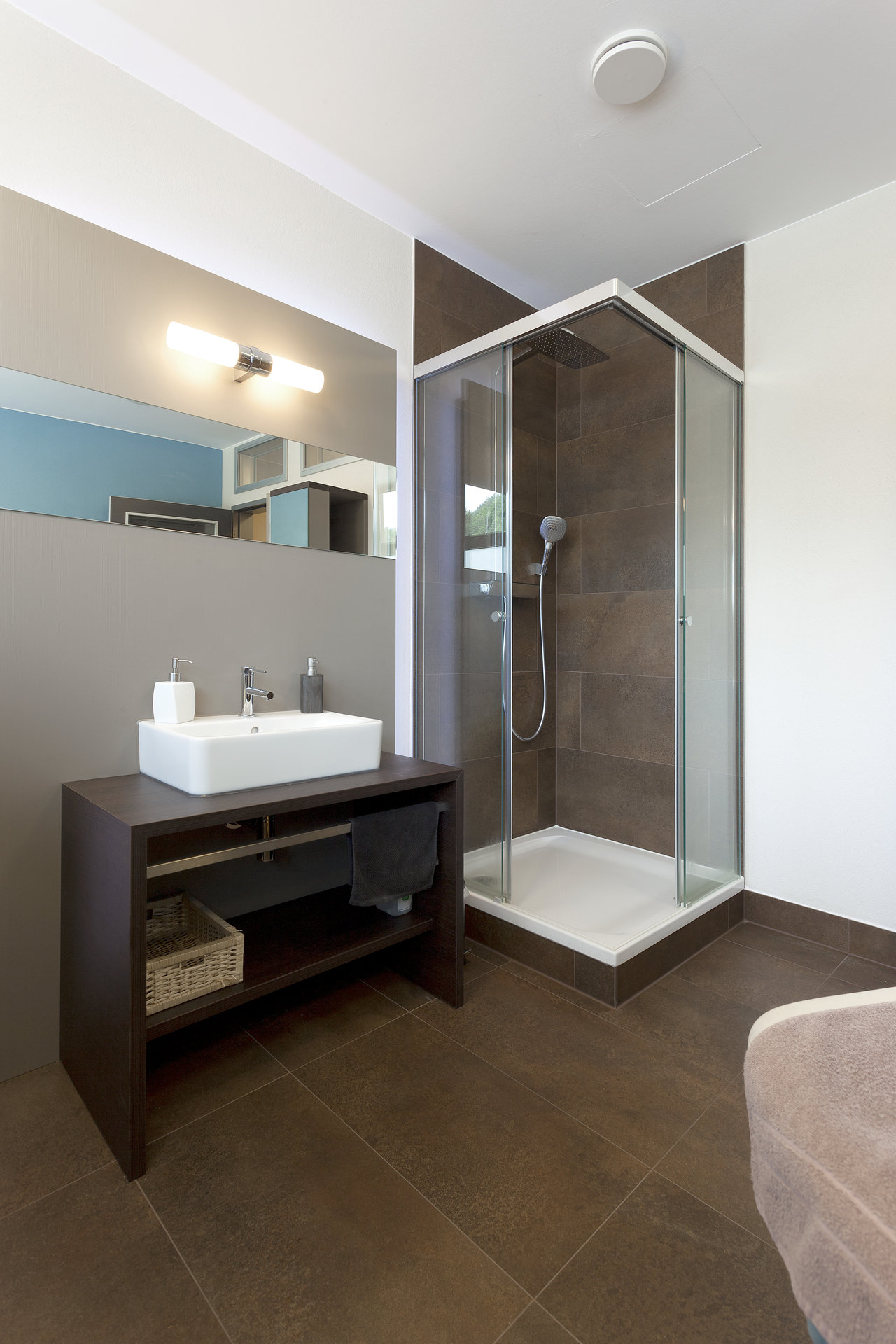 Modern bathroom with dark brown floor and shower wall tiles.