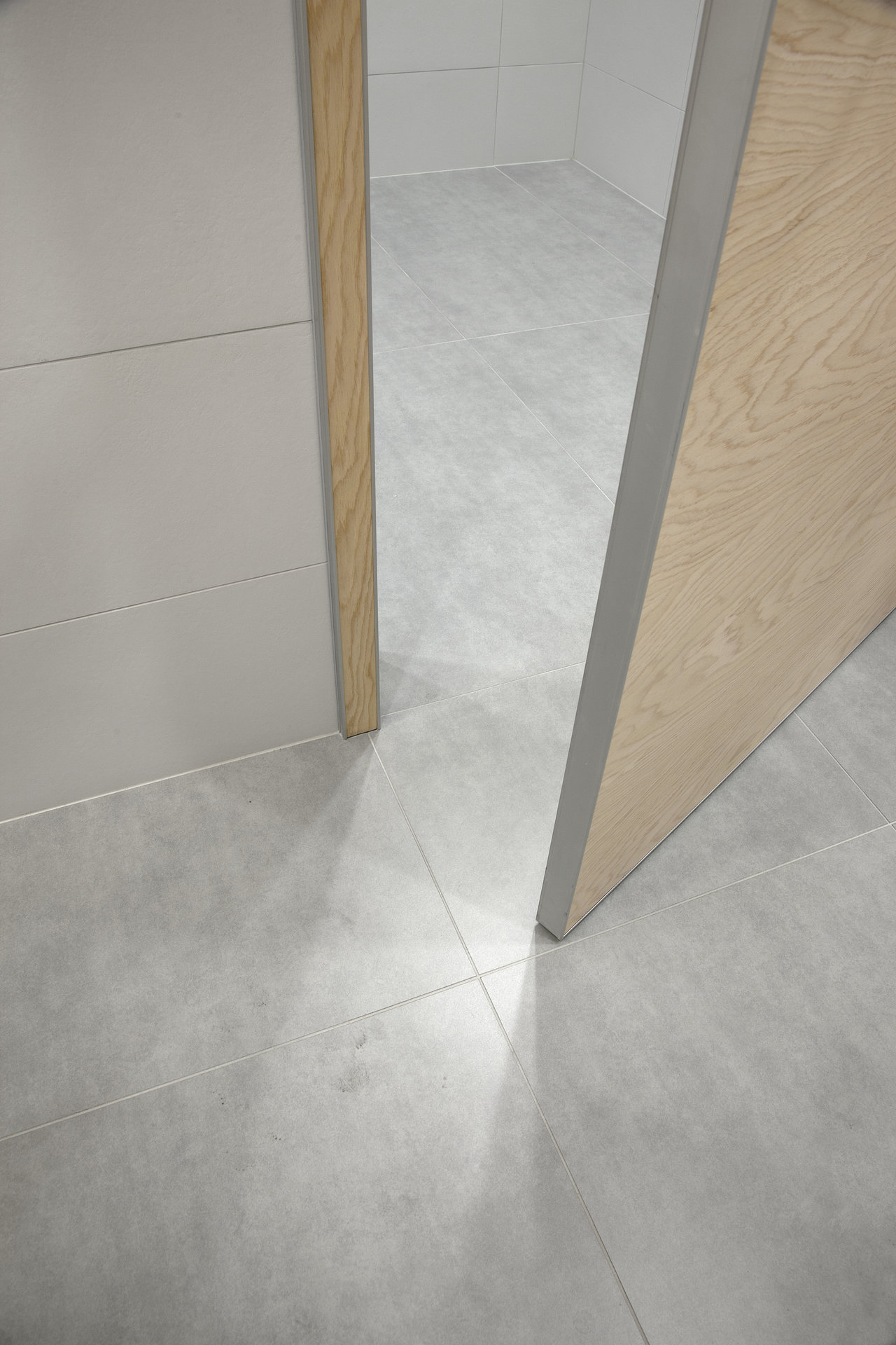 High-quality light grey concrete-effect floor tiles connecting two rooms.