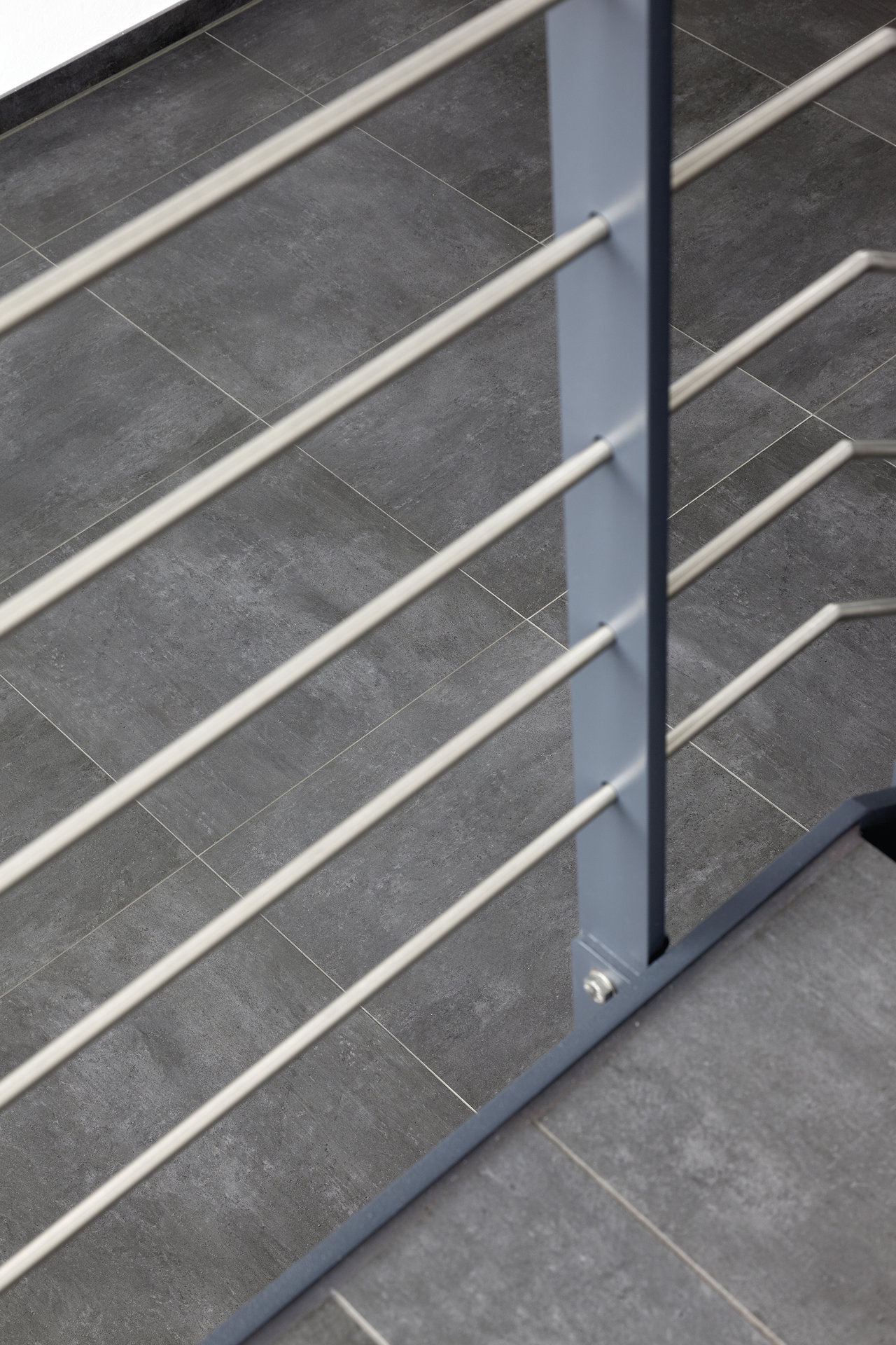 Premium dark grey indoor floor tiles with modern railing.