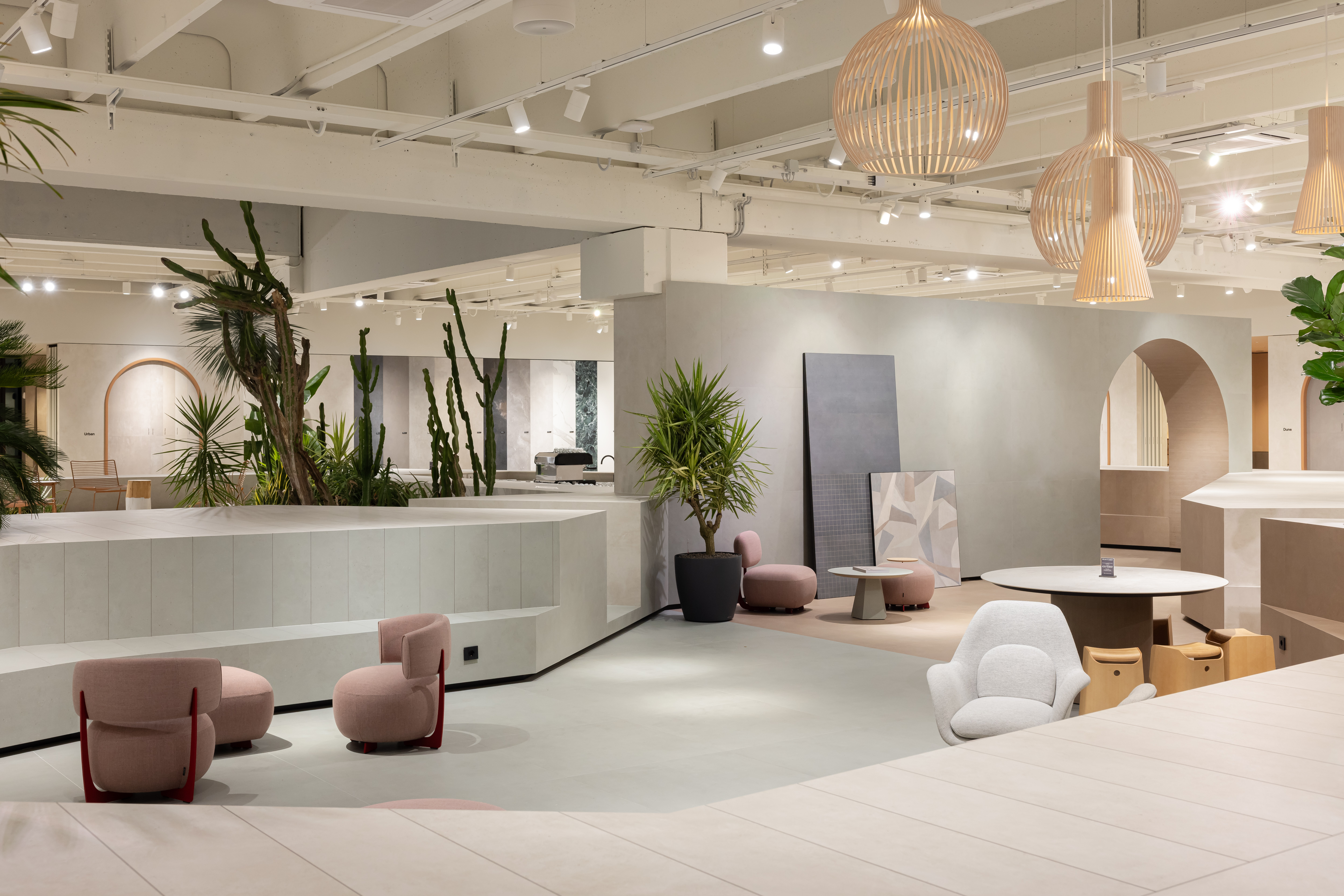 Bright, modern tile showroom with stylish lounge areas and greenery.