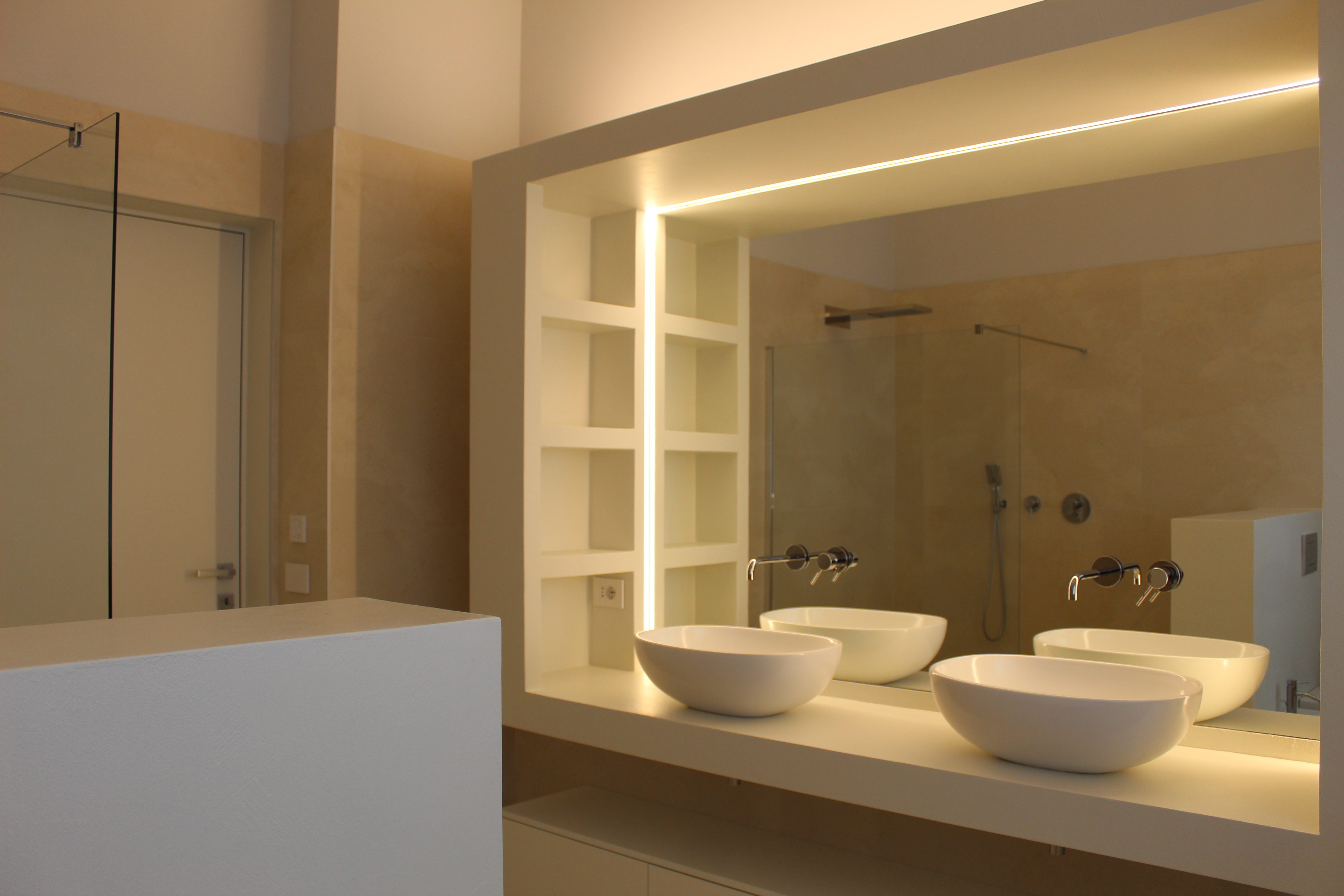 Bright, modern bathroom with large-format wall tiles, double basin, and illuminated mirror.