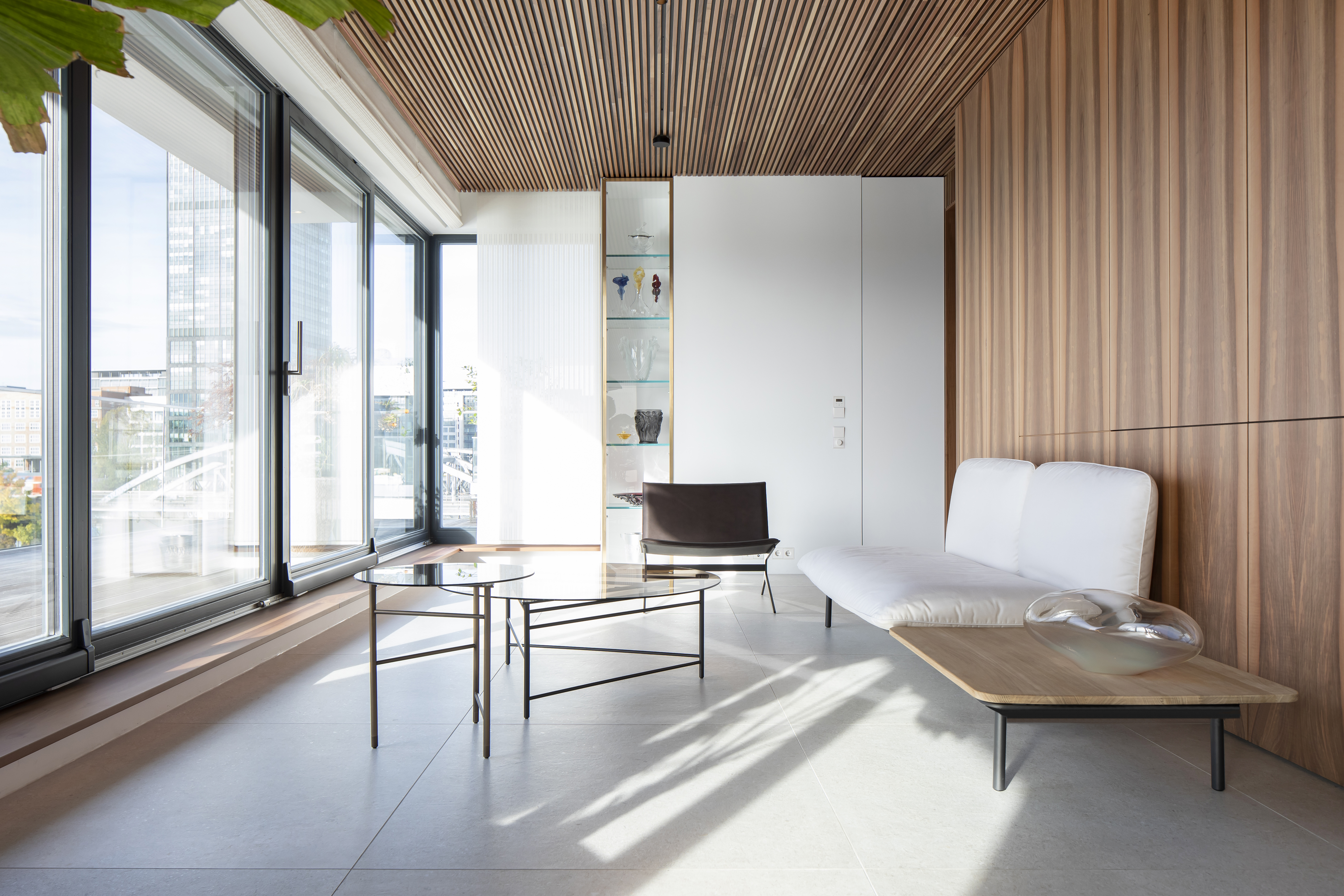 Modern living area with light grey Porcelaingres tiles, wood ceiling, and large windows.