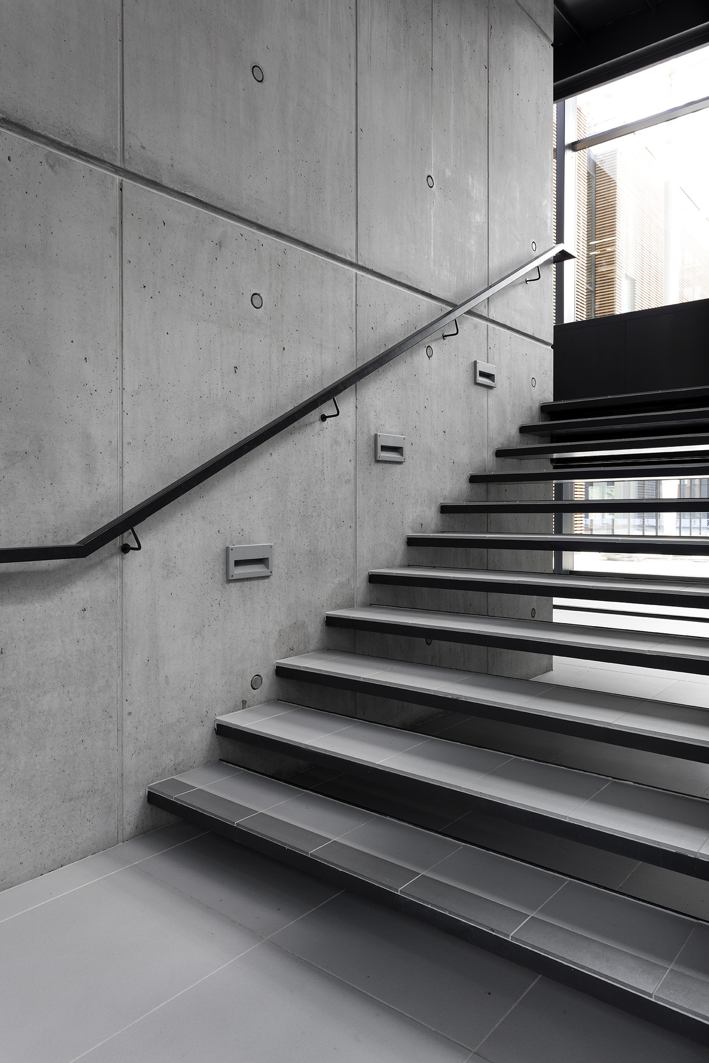 Stylish grey stair tiles with dark accents on a concrete wall.
