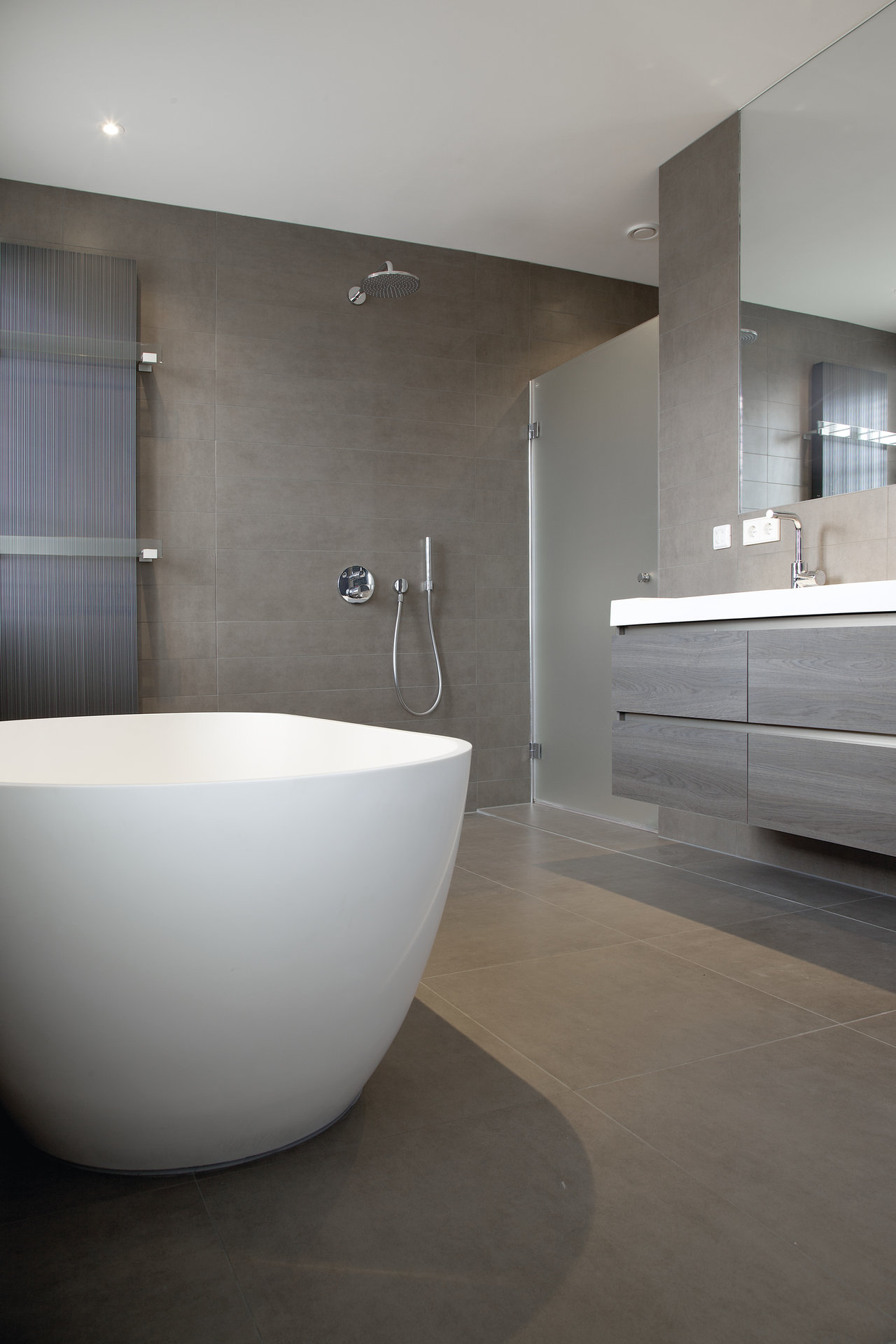 High-quality grey tiles in a modern bathroom with a bathtub and shower.