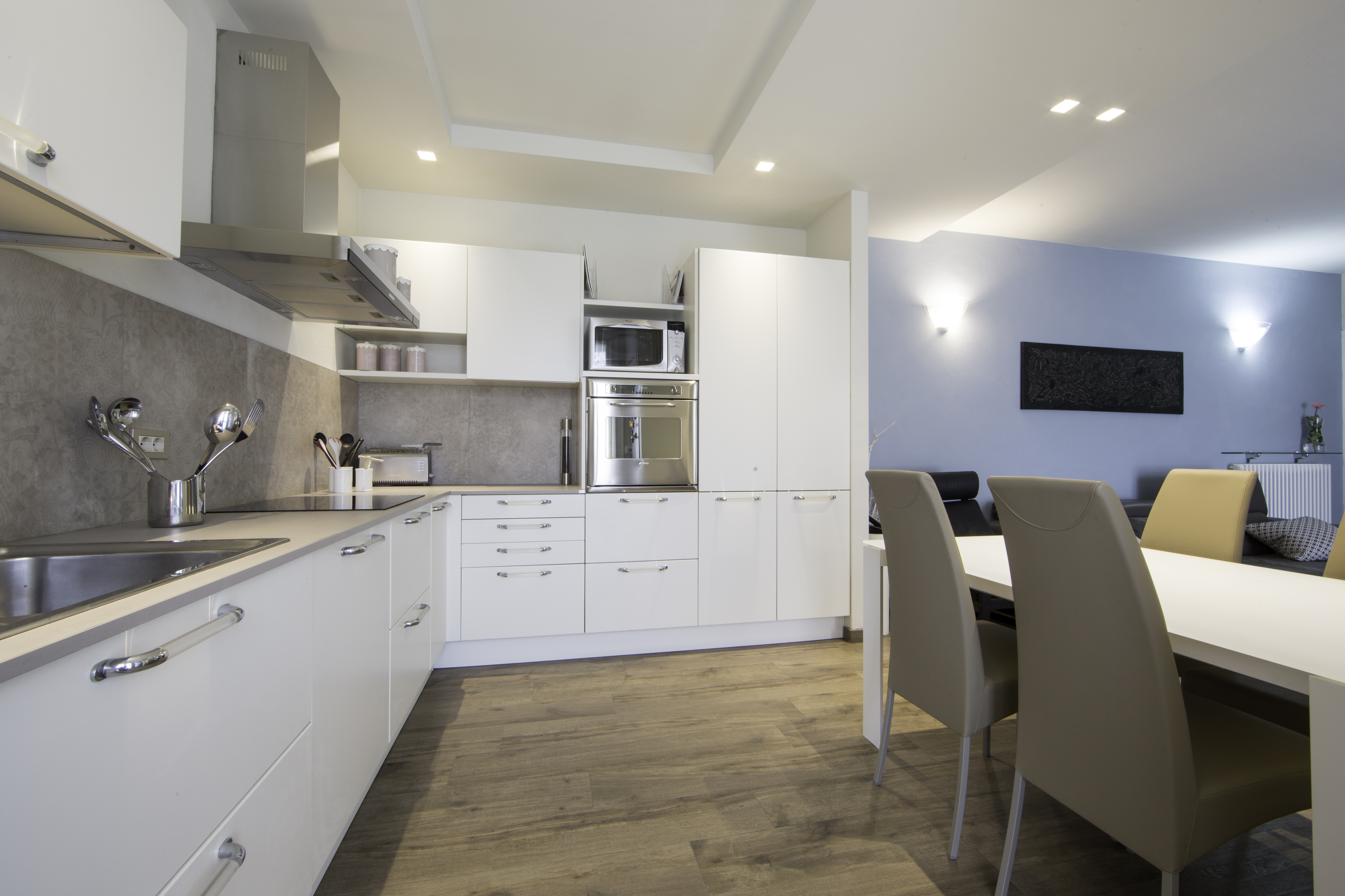Modern kitchen with grey tiles and concrete-look floor tiles in the open-plan dining area.