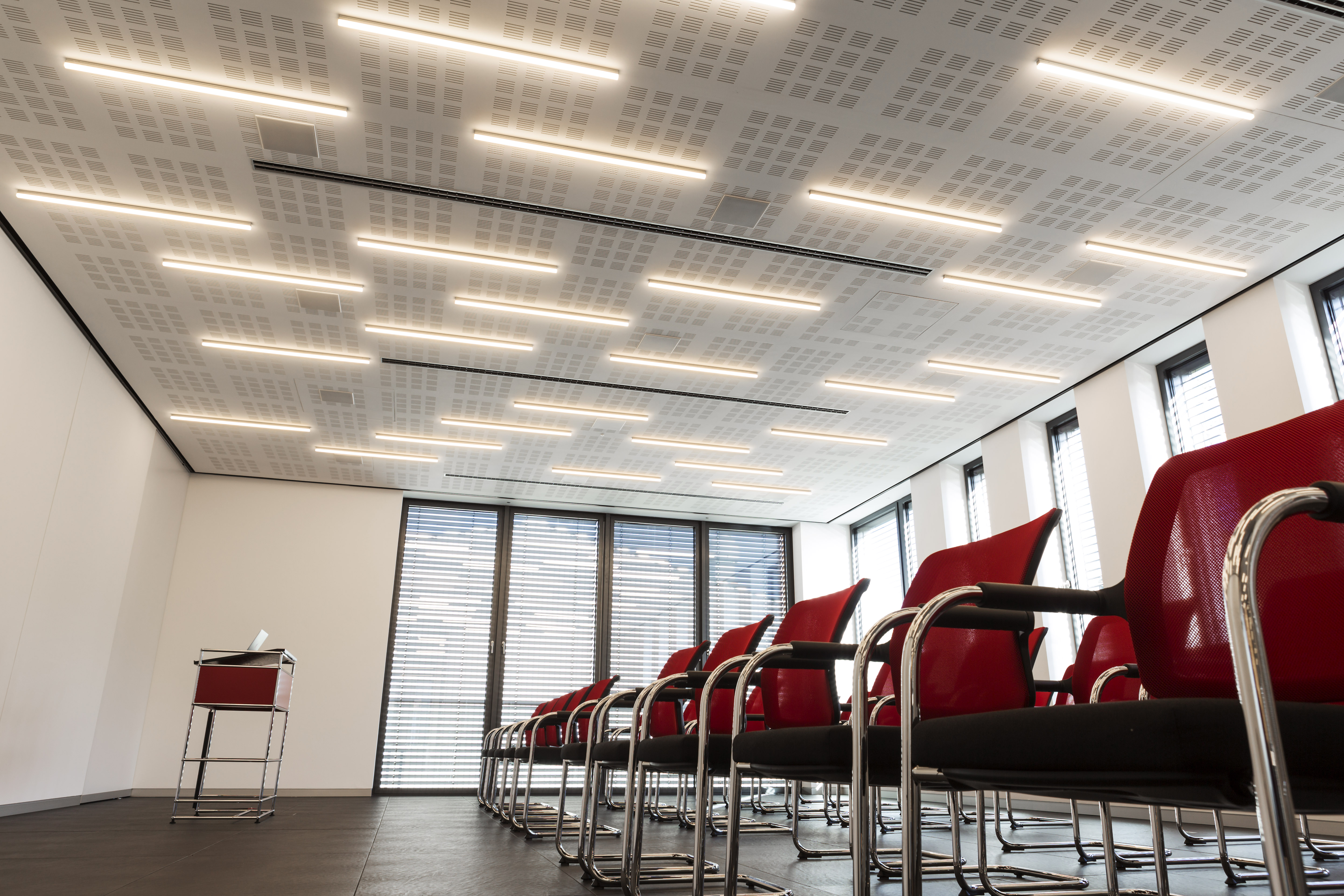 Large-format, dark floor tiles in an elegant conference room with red seating.