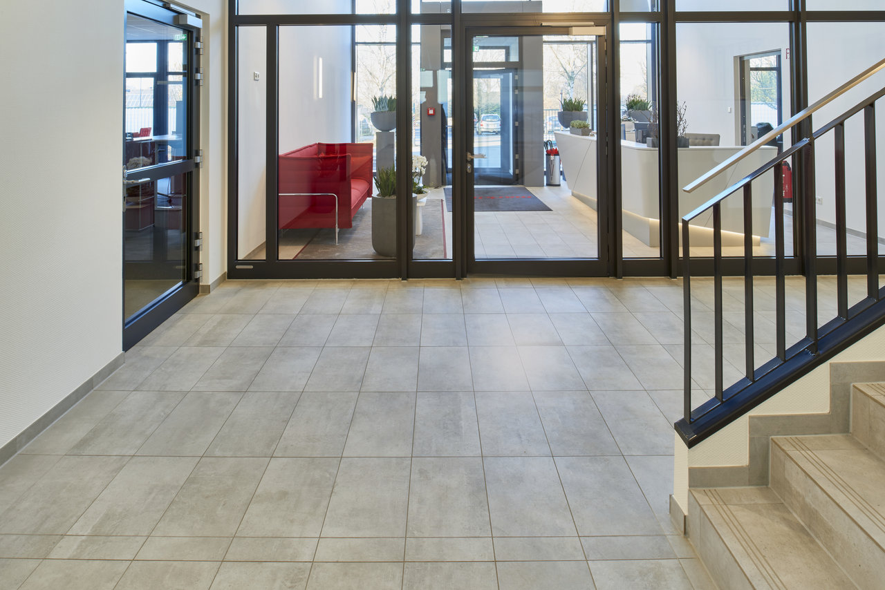 High-quality light grey tiles in a modern foyer with a staircase.