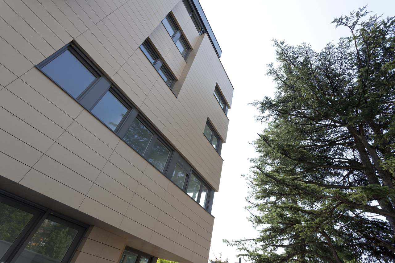 Modern facade with light outdoor tiles and large windows.