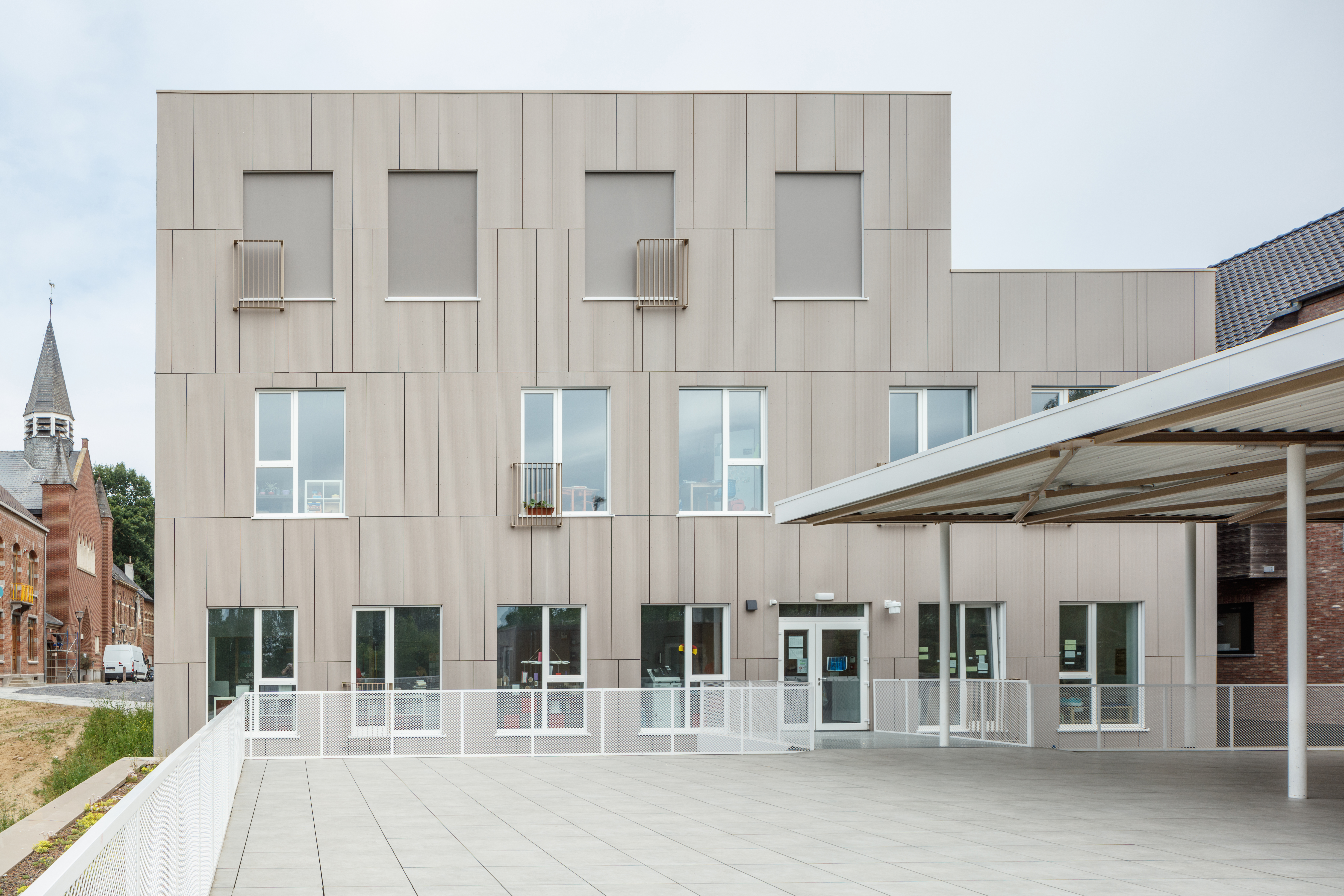 Light-coloured, large-format outdoor tiles on a terrace in front of a modern building.