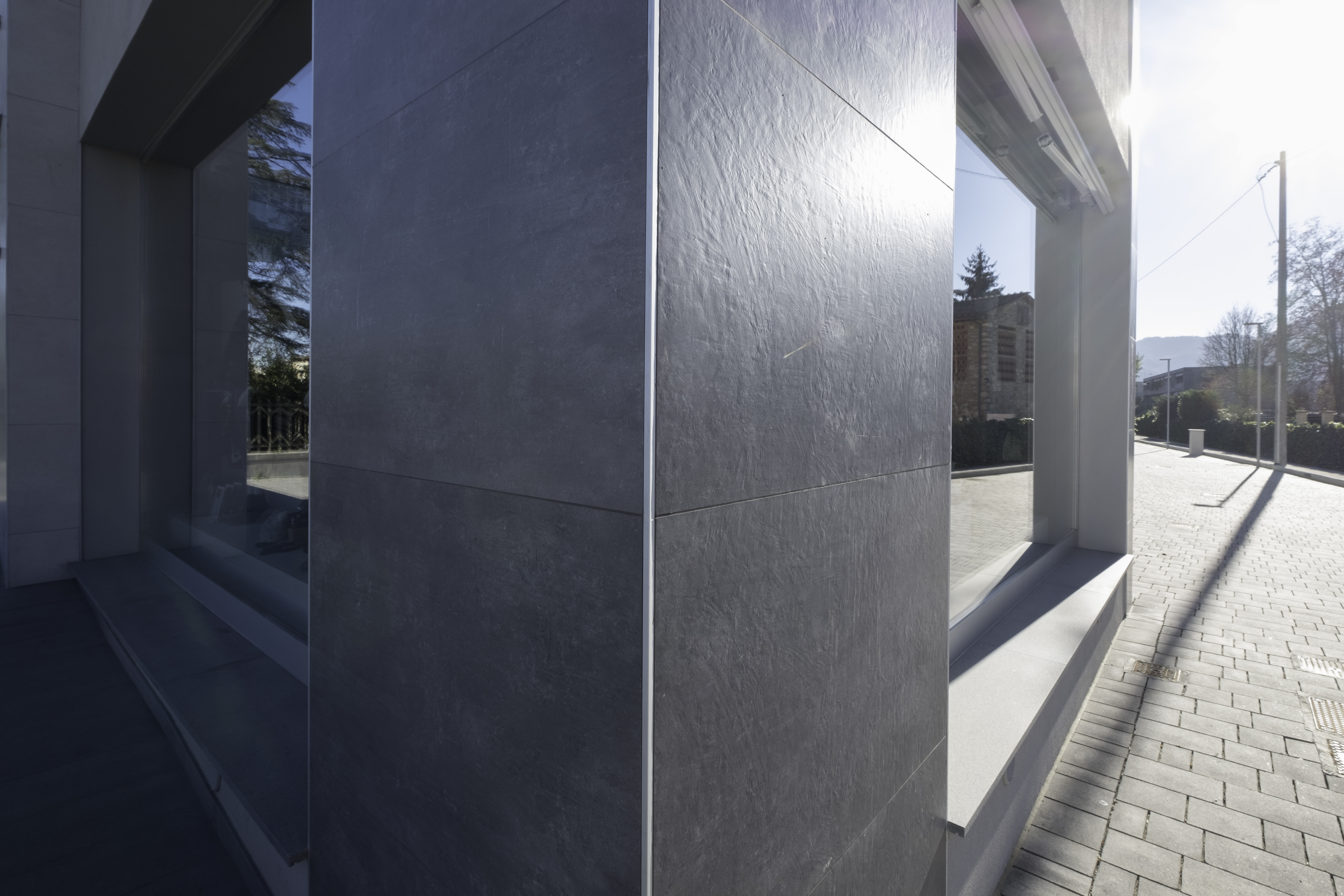 Dark grey textured outdoor facade tiles on a modern building.