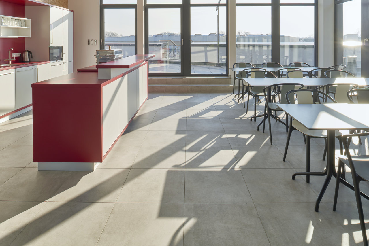 Large-format, bright tiles in a modern kitchen-diner, bathed in natural light.