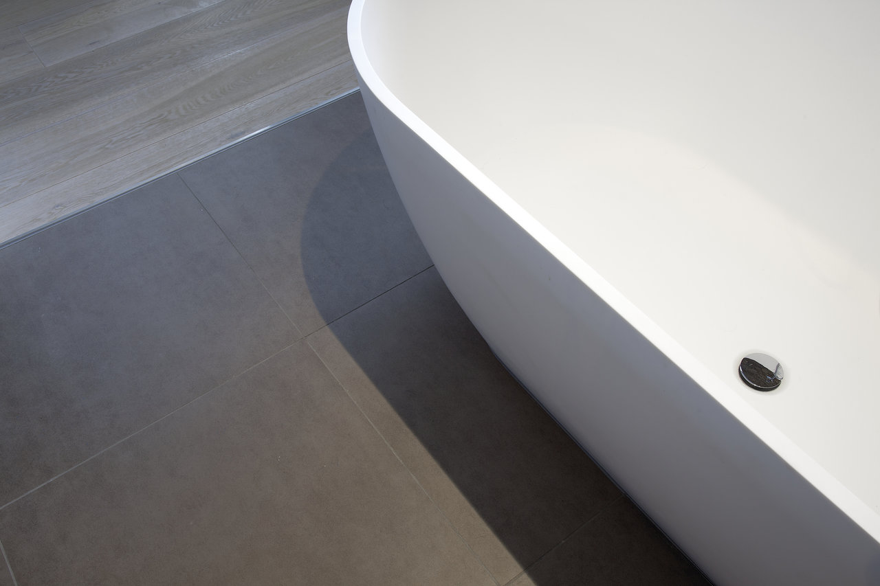 Modern anthracite porcelain stoneware tiles by a freestanding bath.