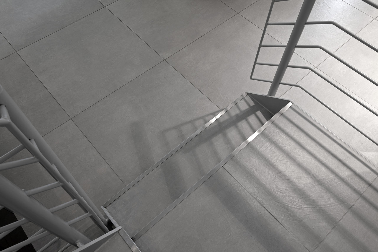 Large-format, light grey concrete-effect tiles in a modern staircase.