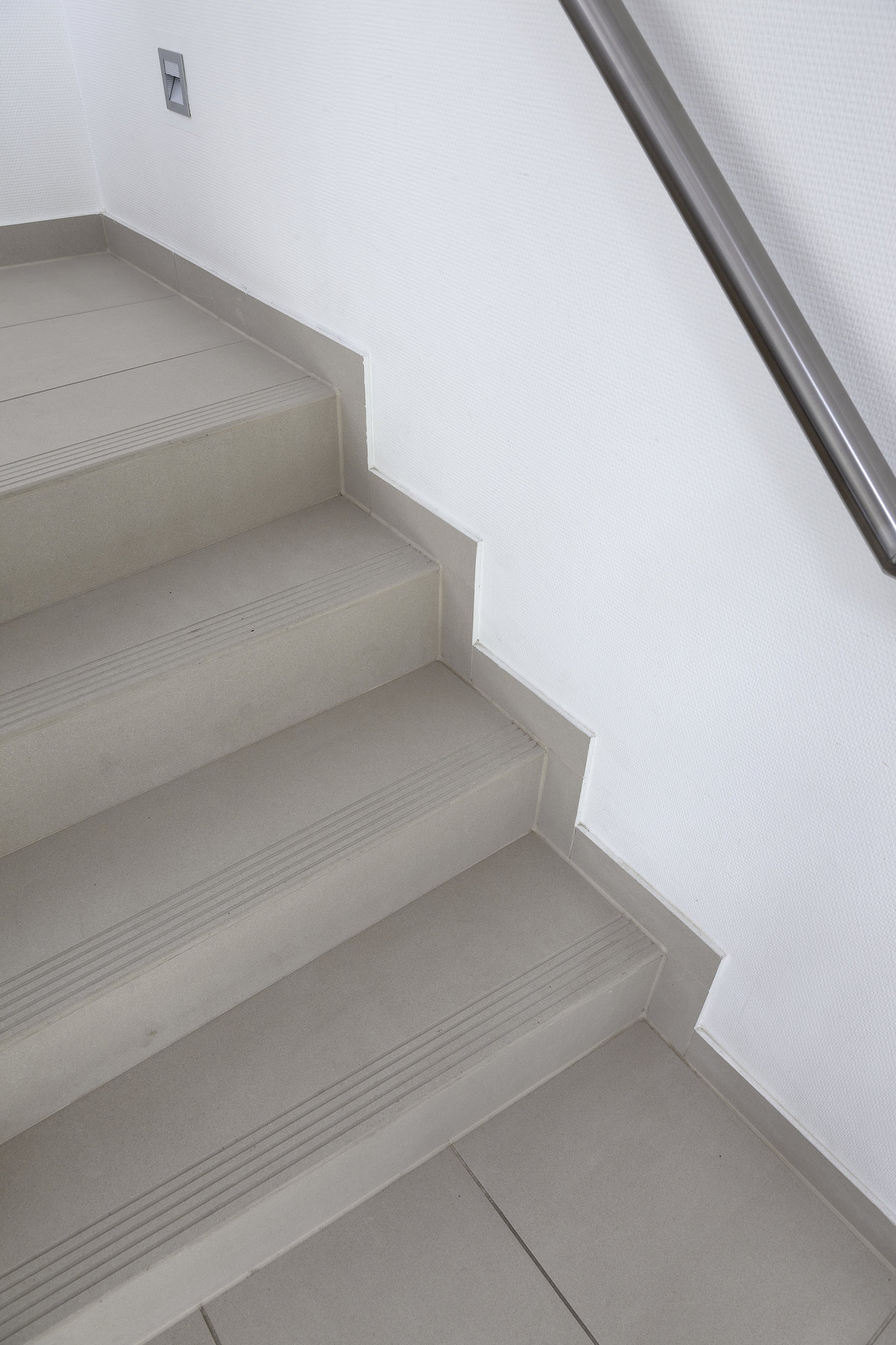 High-quality light grey tiled stair treads with anti-slip grooves.