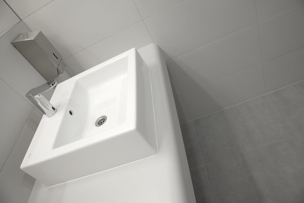 Light grey wall and floor tiles for a modern bathroom with a white basin.