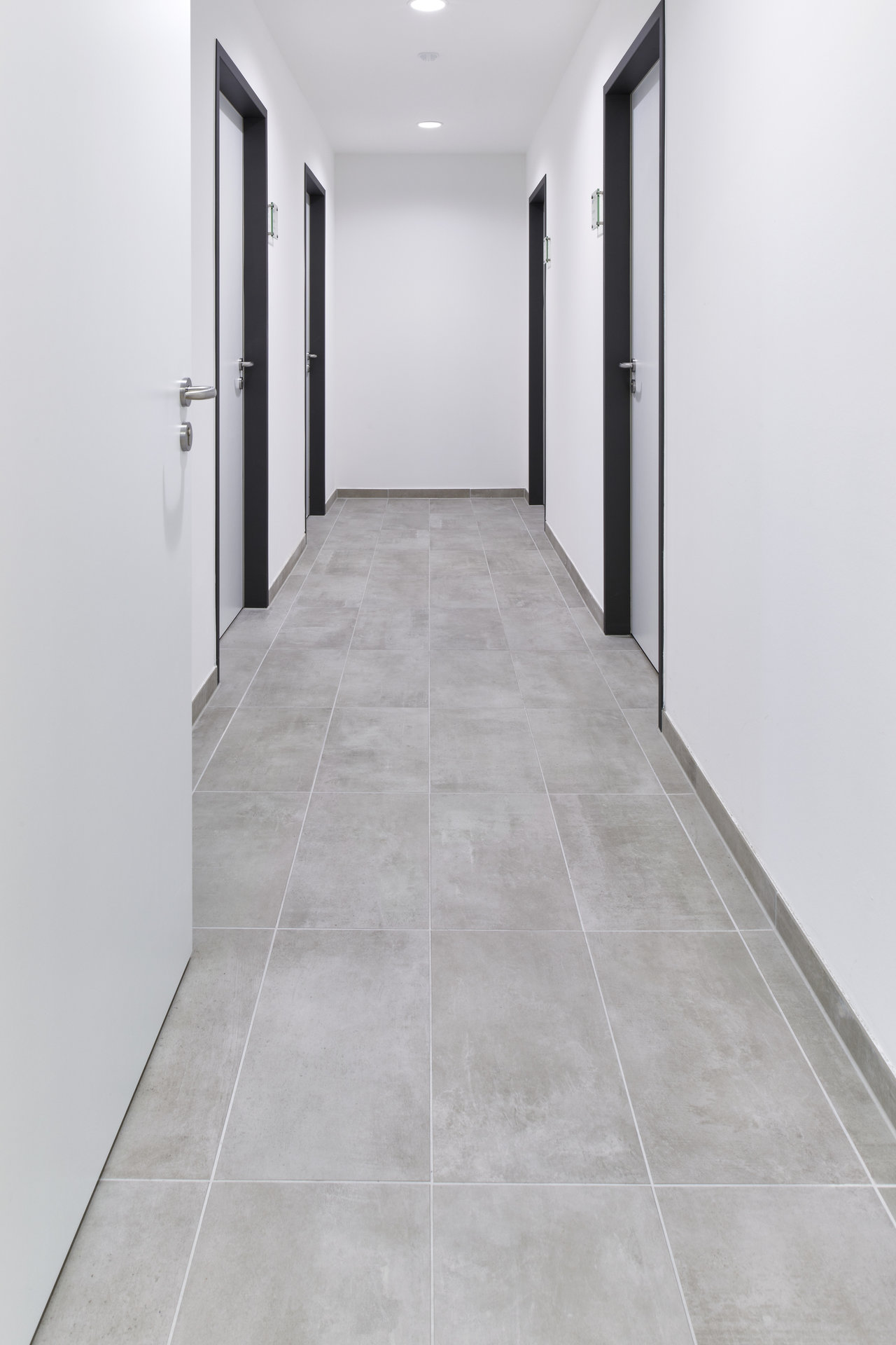 Modern hallway with elegant, light grey tiles and white walls.
