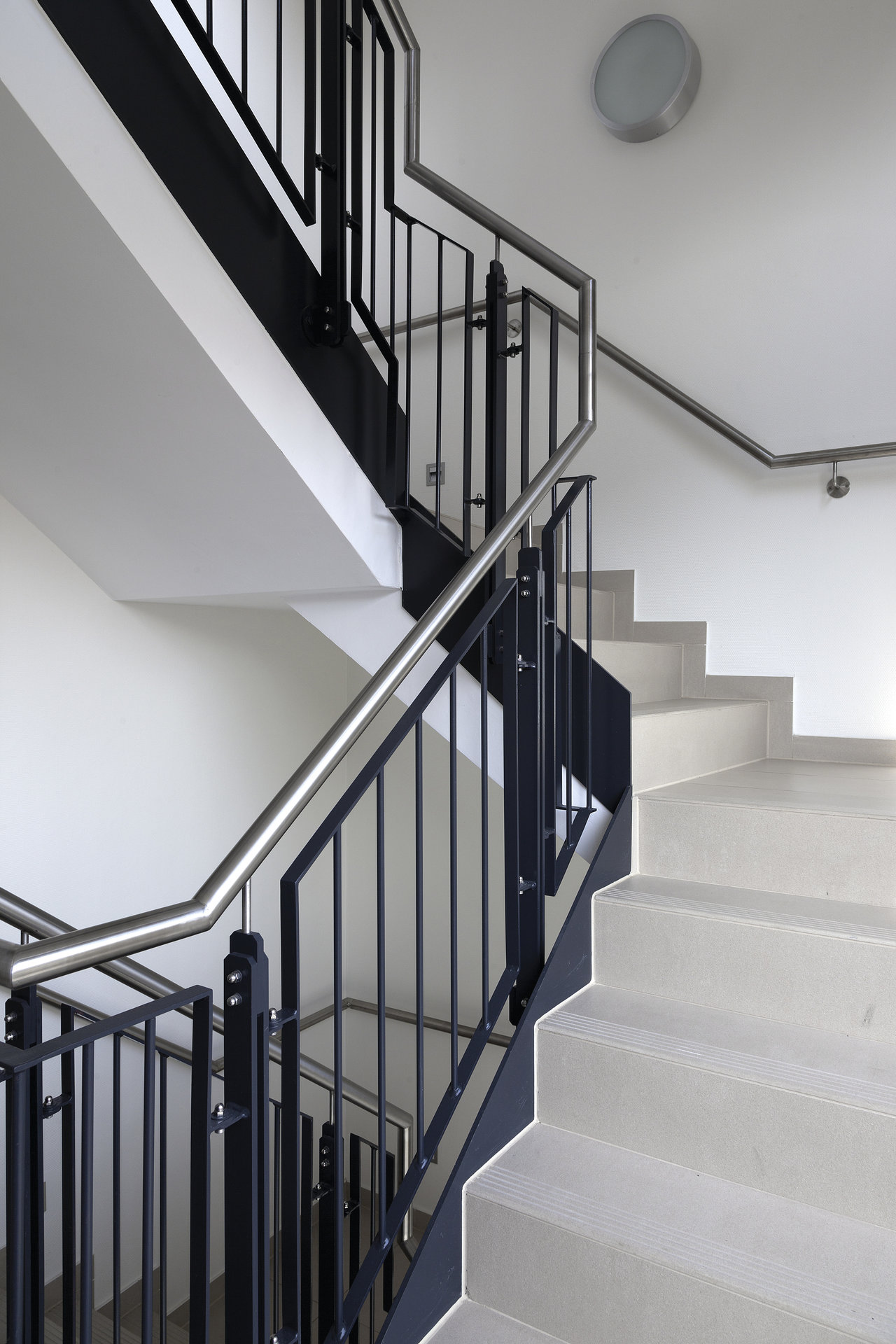 High-quality light grey tiles on a modern indoor staircase with metal railing.
