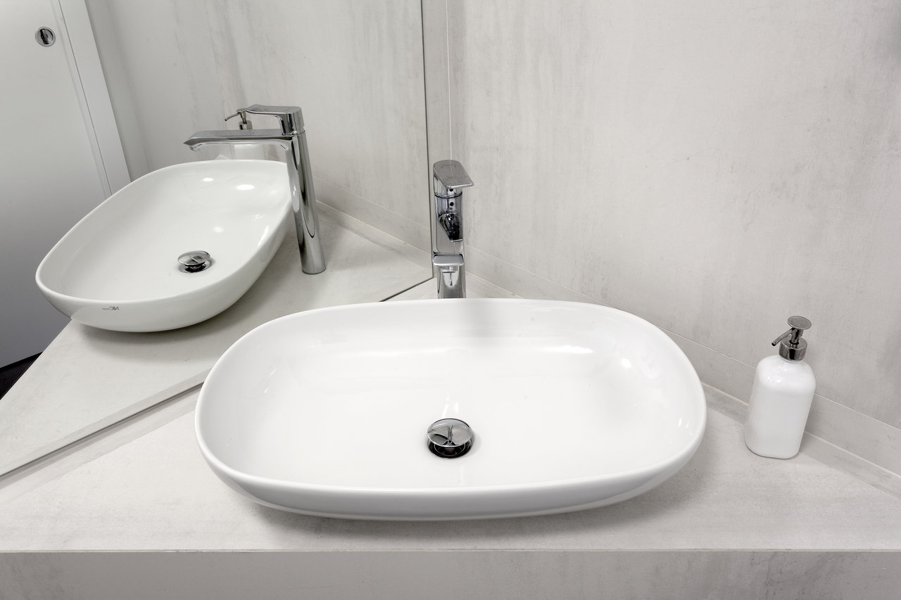 Elegant bathroom with white countertop basin and light, modern tiles.