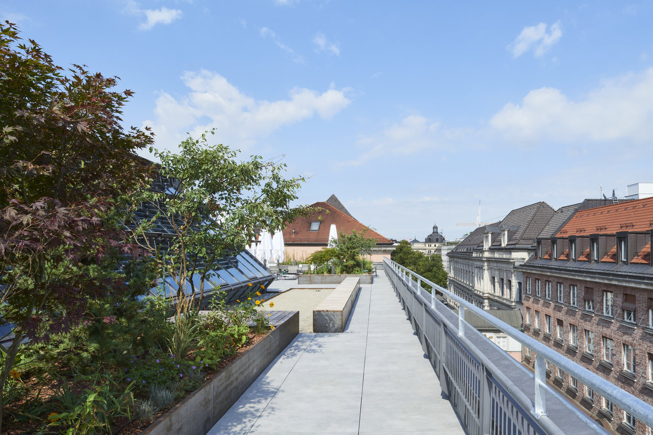 Light outdoor tiles on a rooftop terrace with plants and city view.