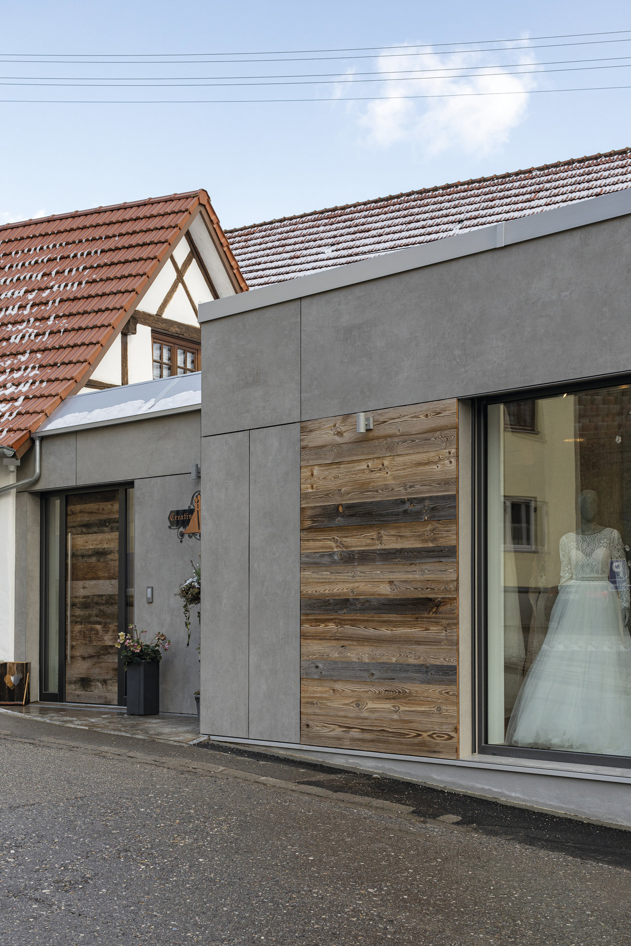 Contemporary facade with large-format grey tiles and reclaimed wood accents.