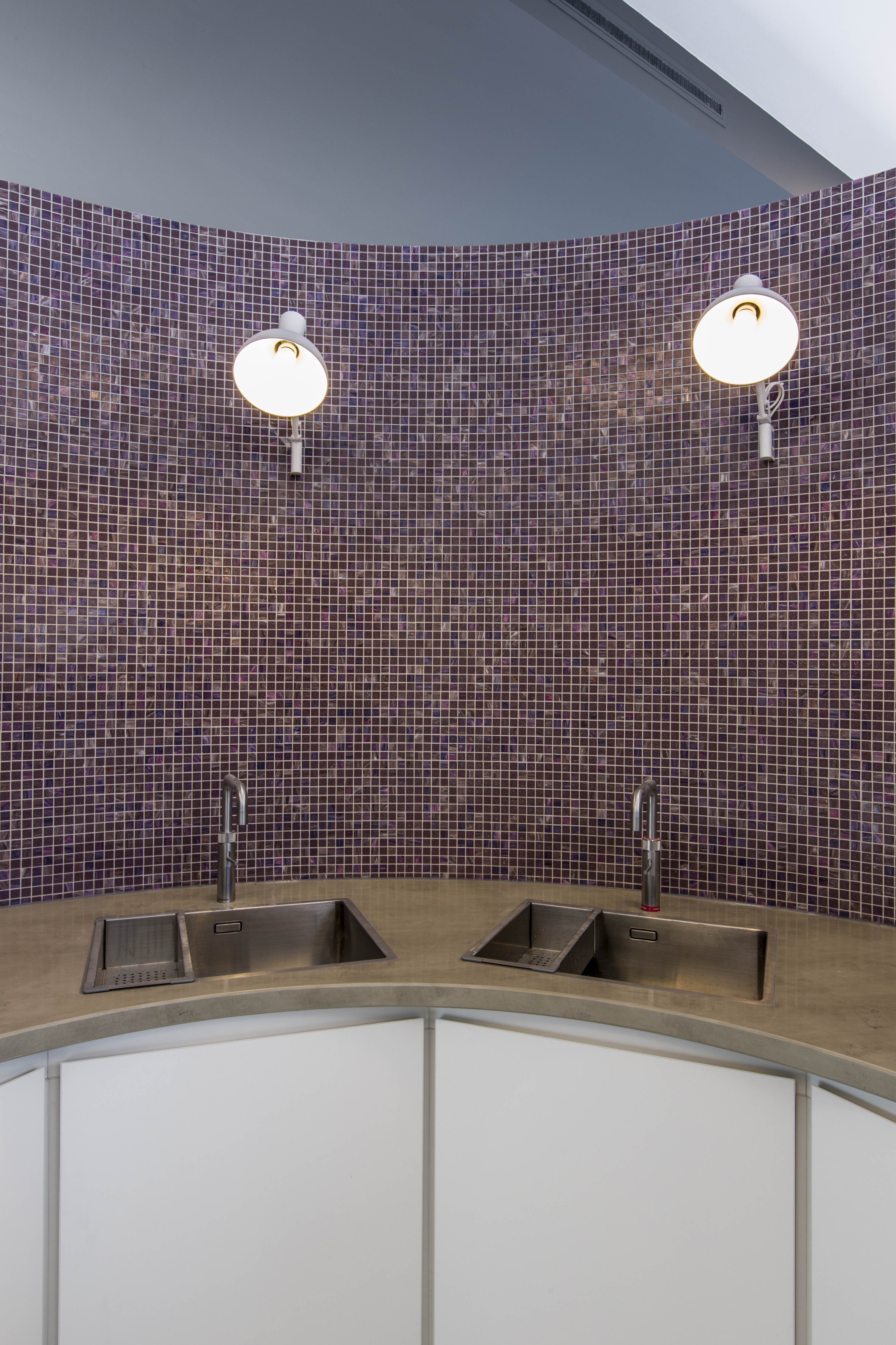 Modern bathroom design with glossy purple mosaic tiles and two stainless steel sinks.