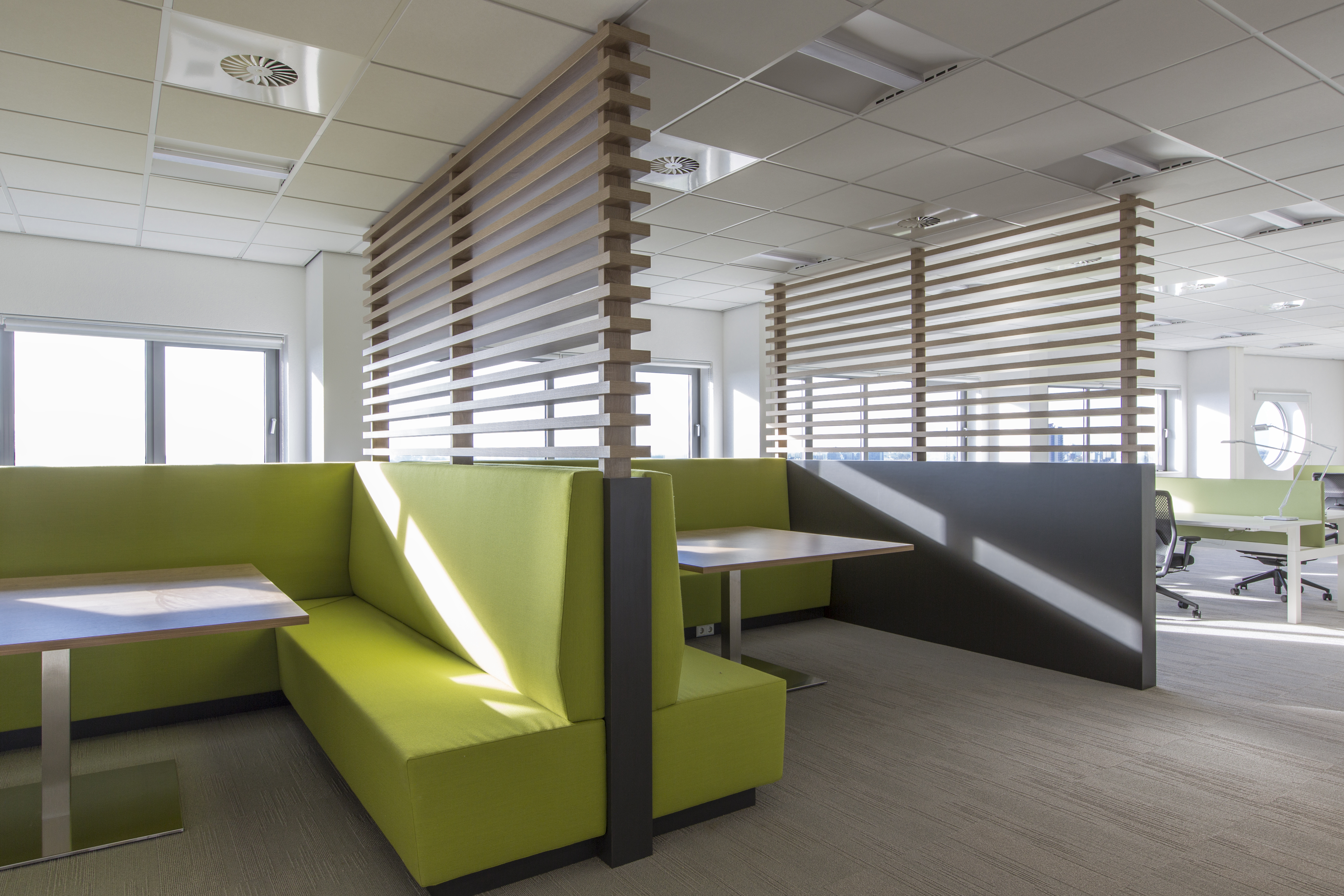 Modern office with green seating areas and light flooring, ideal for our indoor tiles.