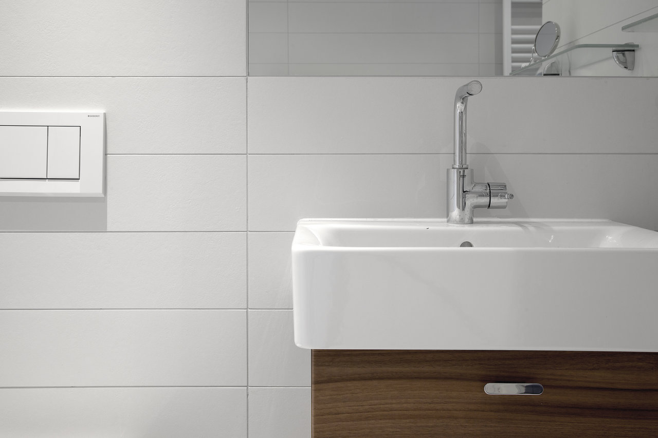White, rectangular wall tiles in a modern bathroom with a washbasin.