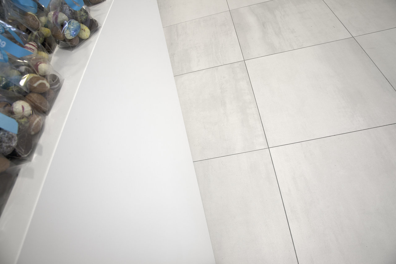 Light, large-format grey floor tiles with dark grout.