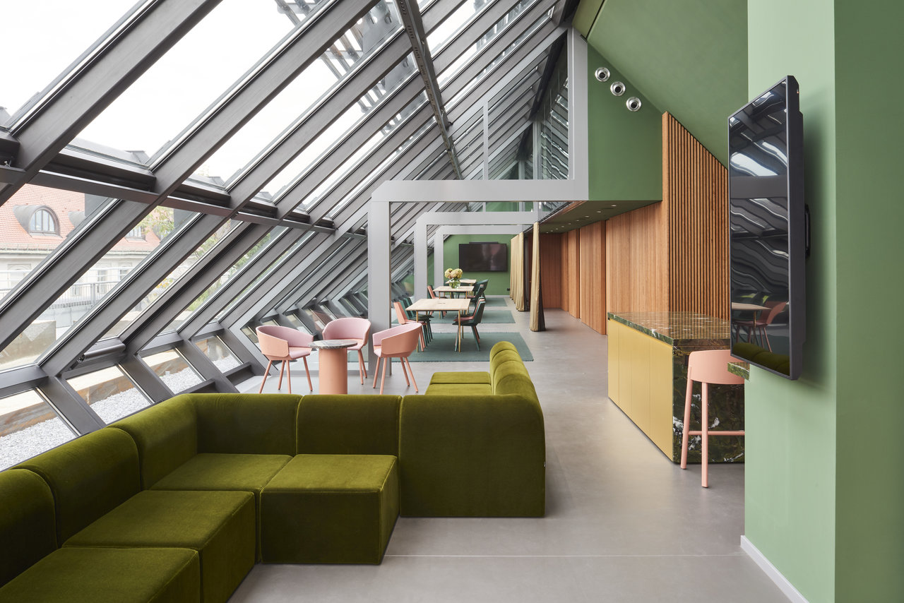 Modern, bright room with large-format tiles, green lounge corner, and glass front.