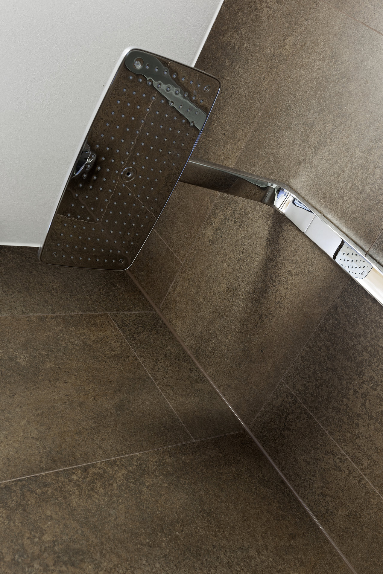 Premium dark brown shower tiles with a modern rain shower.