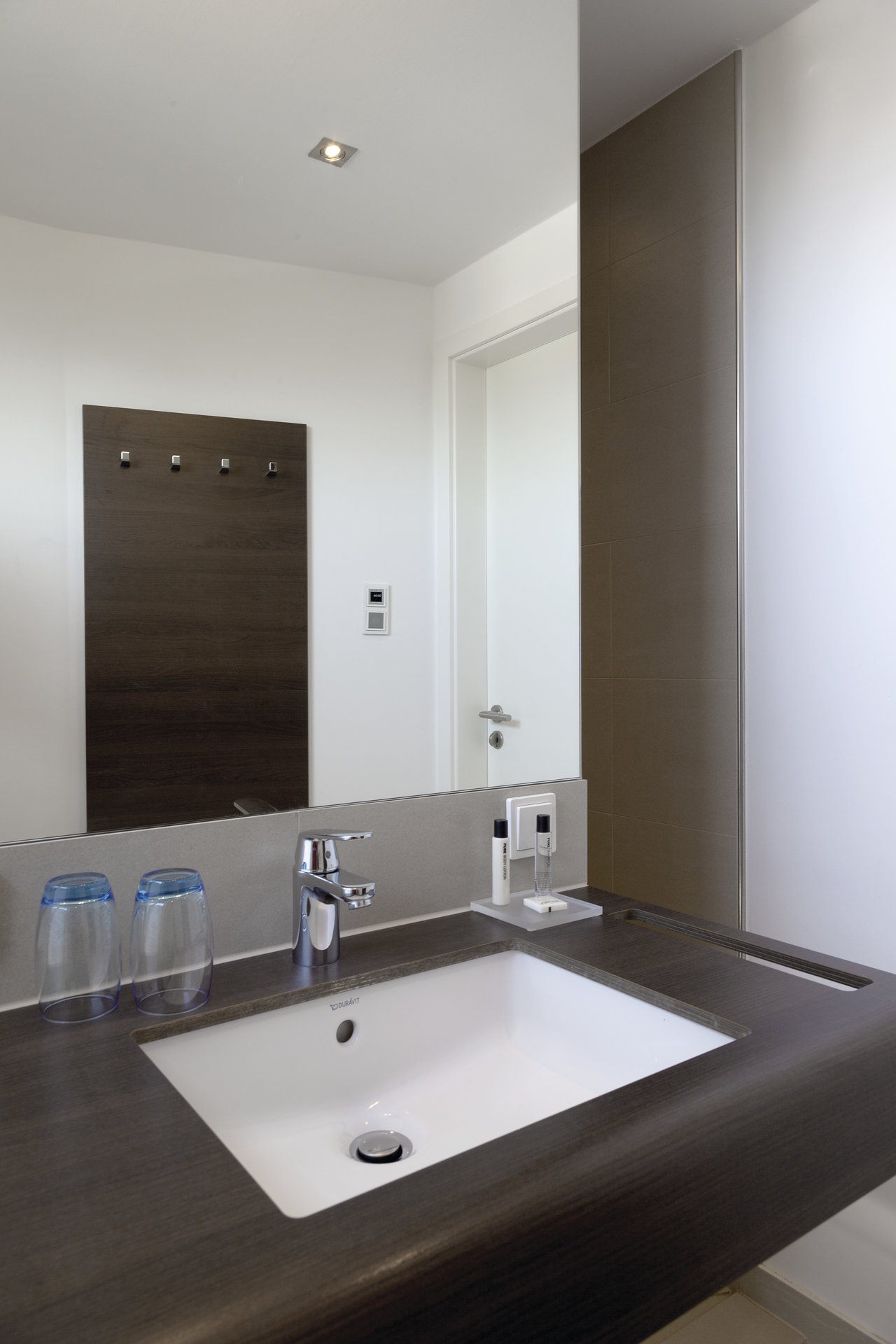 Modern bathroom with dark vanity top and white sink, matching elegant tiles.