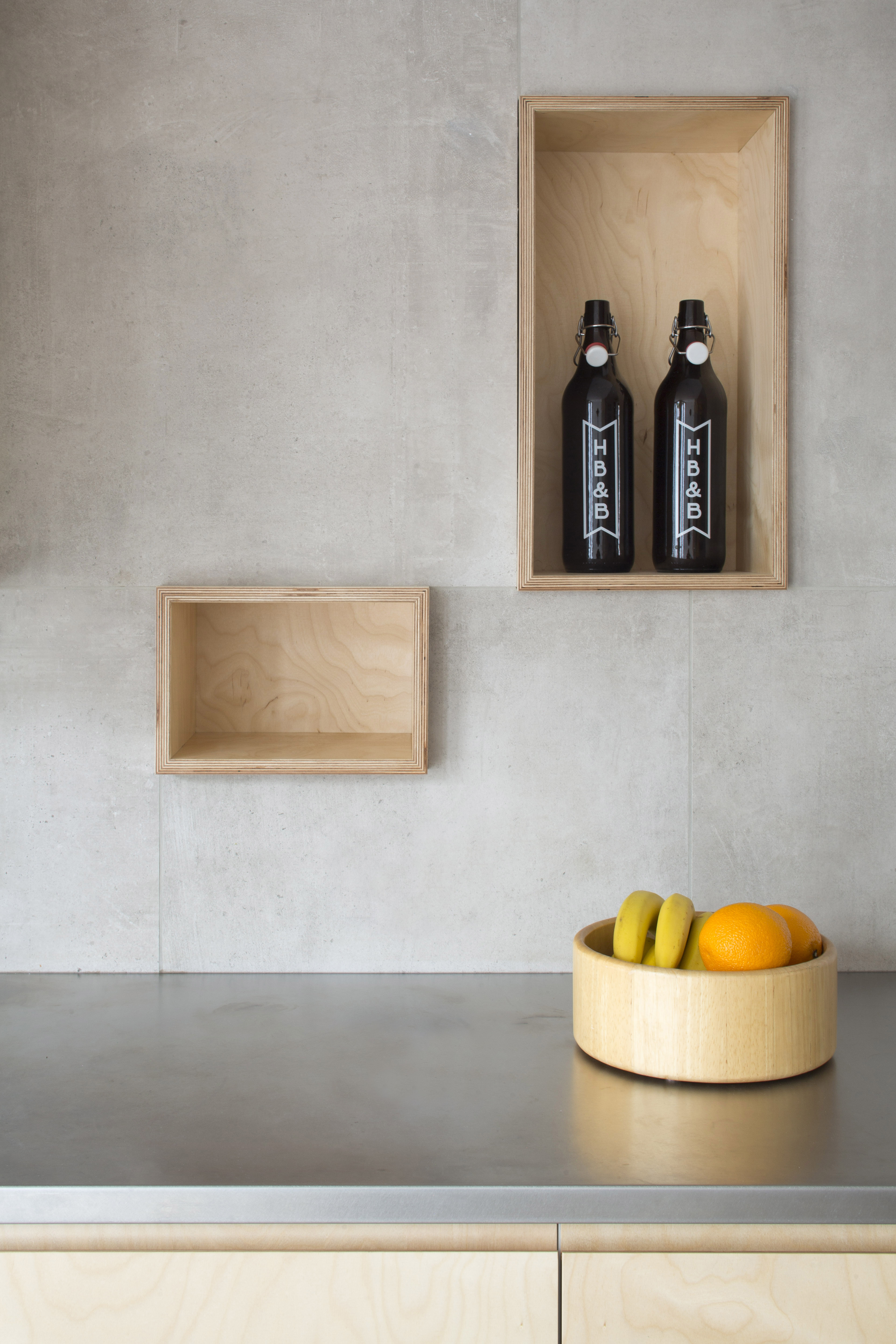 Modern kitchen splashback with light grey tiles, wooden niches and a metal worktop.