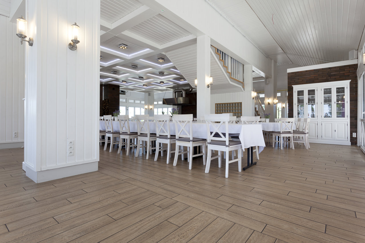 Bright dining room with Porcelaingres wood-look tiles and white tables.