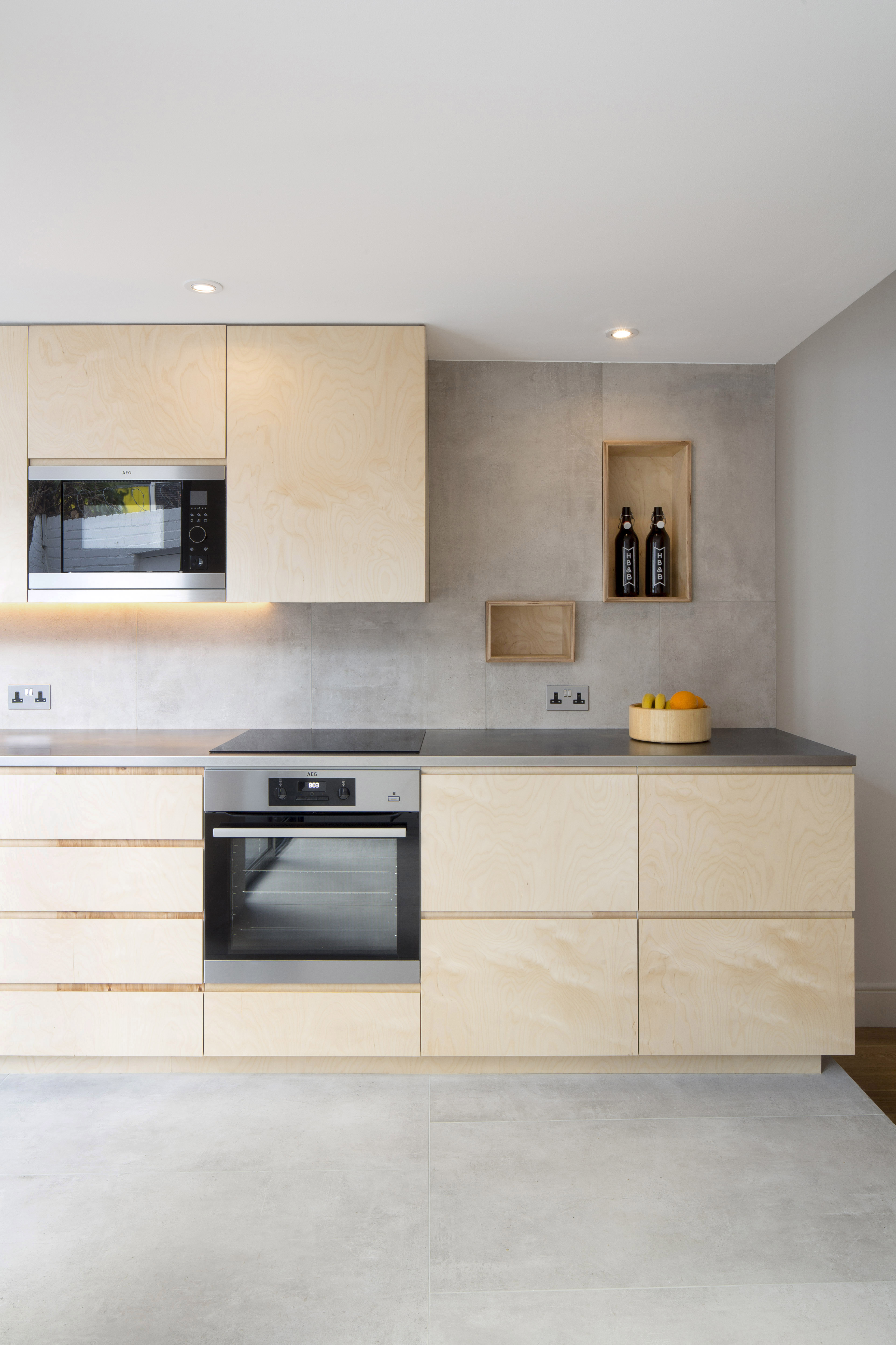 Modern kitchen with light grey floor tiles and matching concrete-effect splashback, combined with wooden fronts.