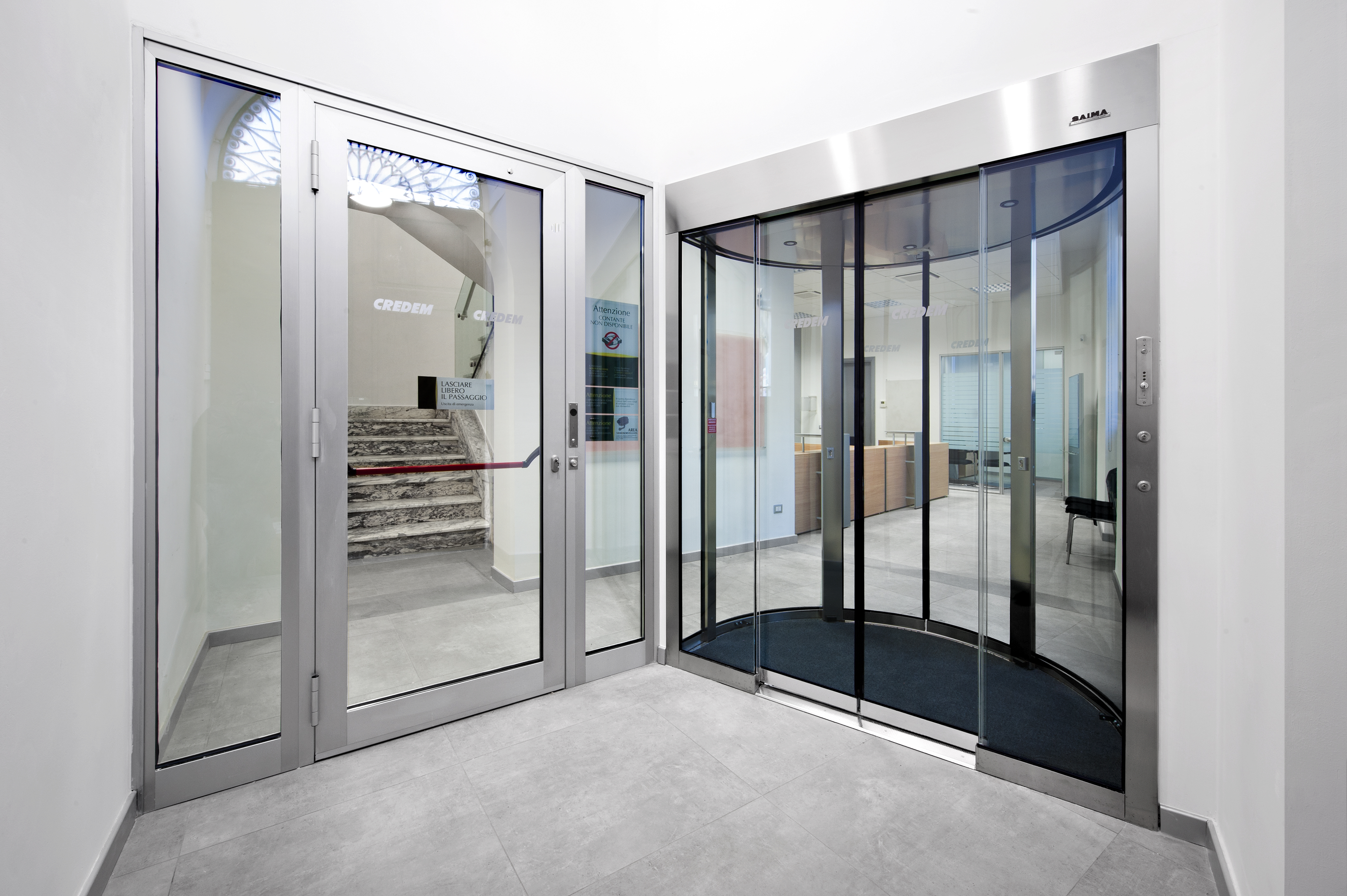 High-quality, light grey tiles in a modern entrance with glass doors.