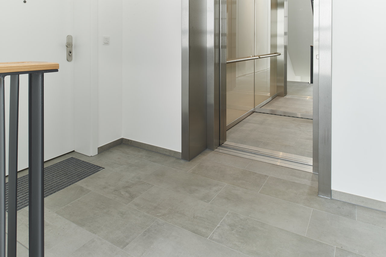 High-quality, light grey tiles for modern hallways and lifts.