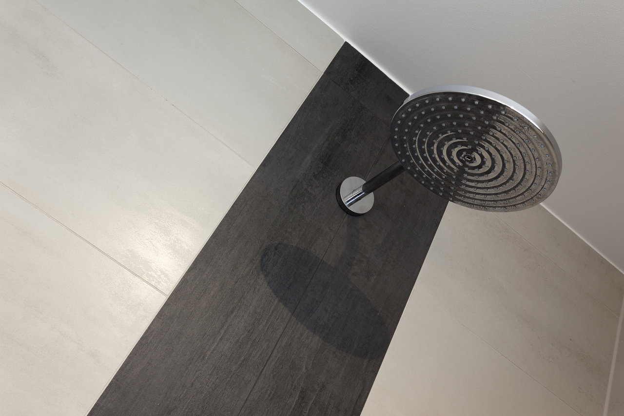 Modern shower wall, contrasting light grey and anthracite tiles, rain shower.