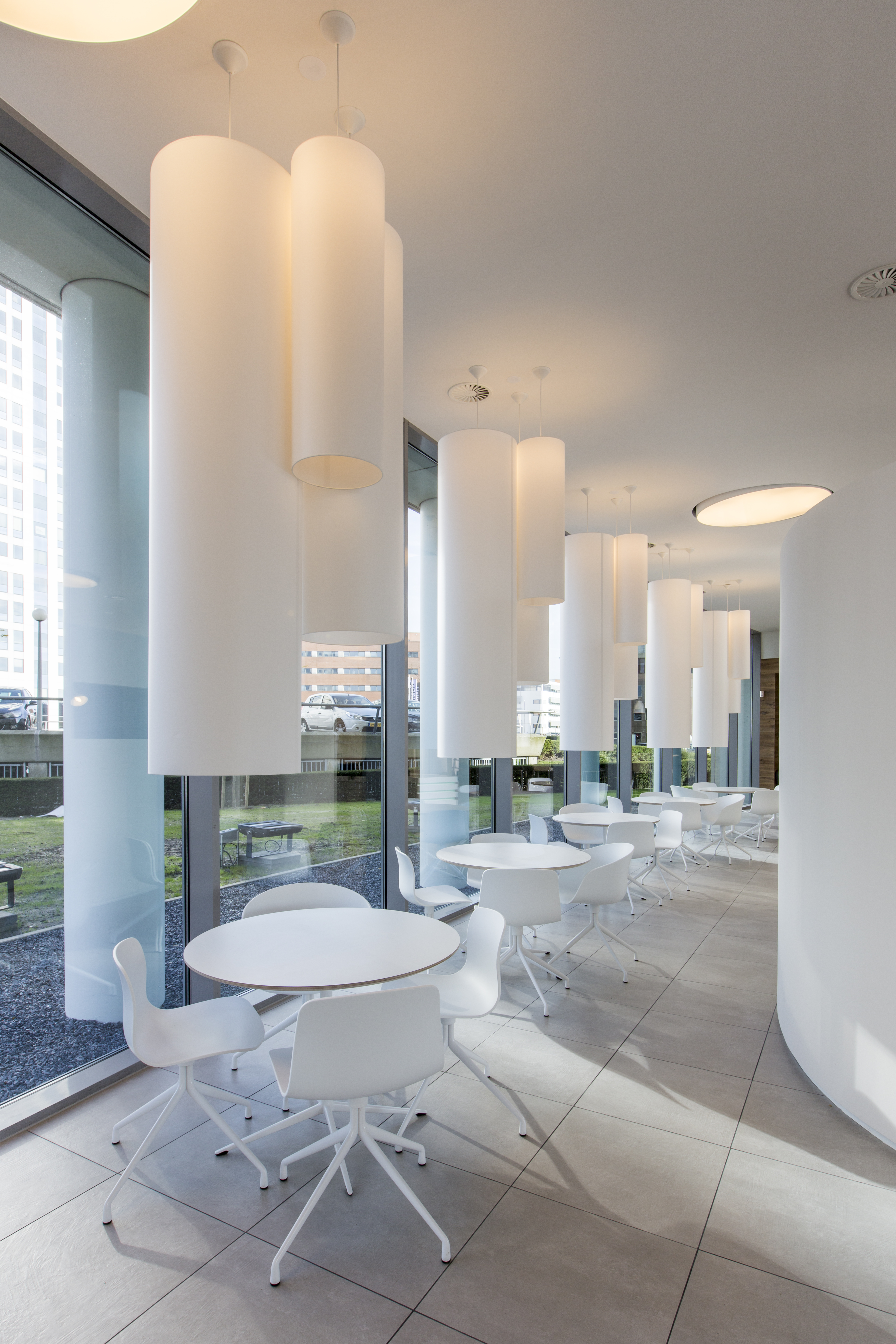 Modern lounge with light grey floor tiles, white tables, and minimalist design.