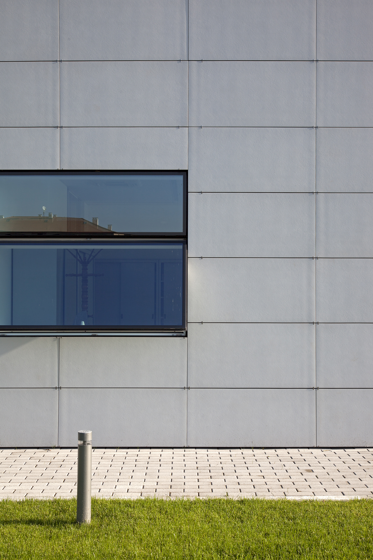 Modern exterior facade with large-format tiles and light paving.