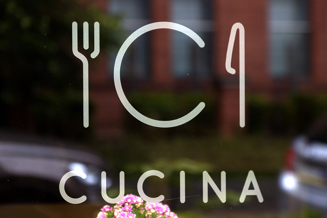 CUCINA lettering and stylized cutlery logo on glass.
