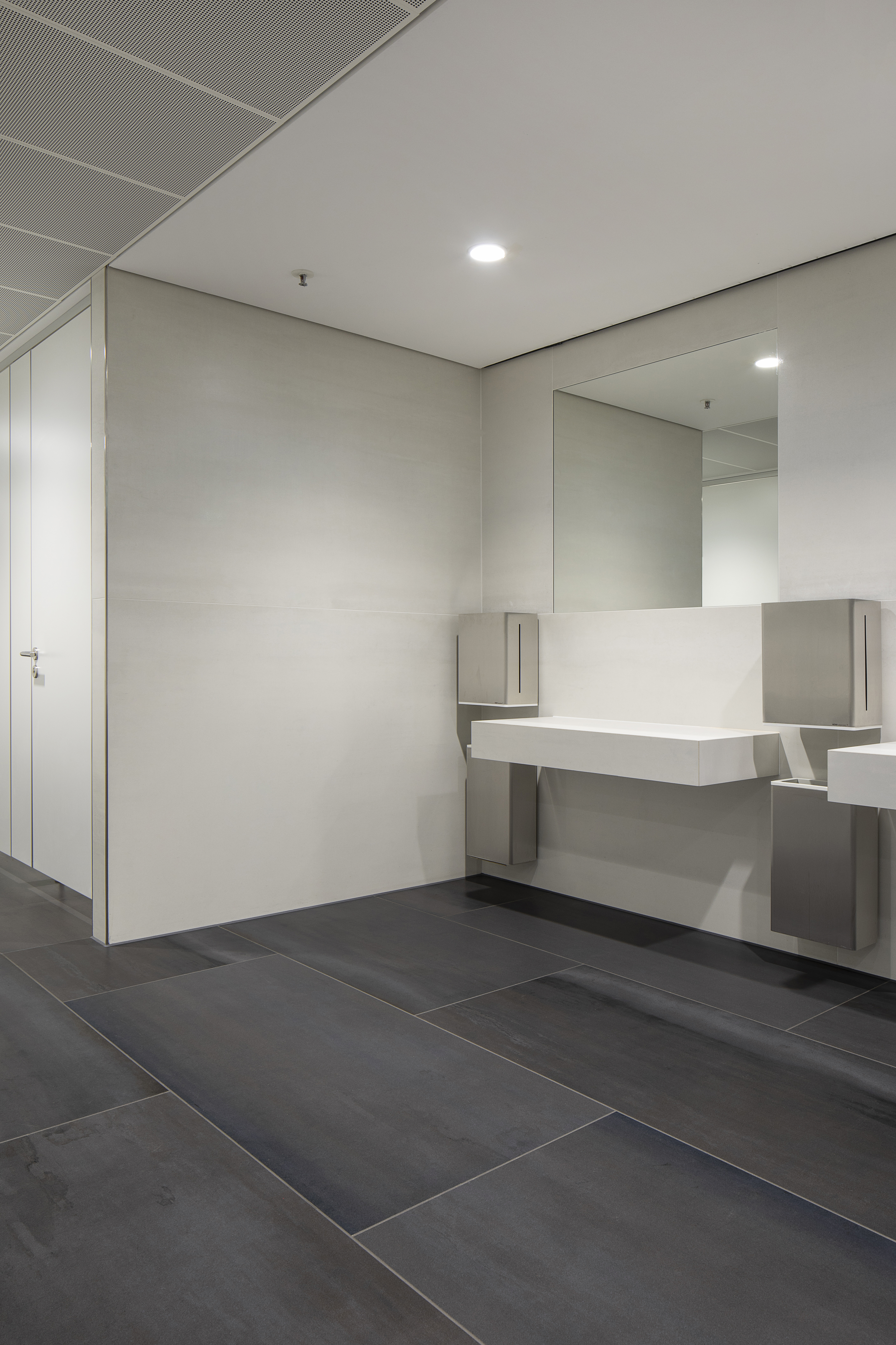 Large-format anthracite floor and light wall tiles in a modern laundry room.