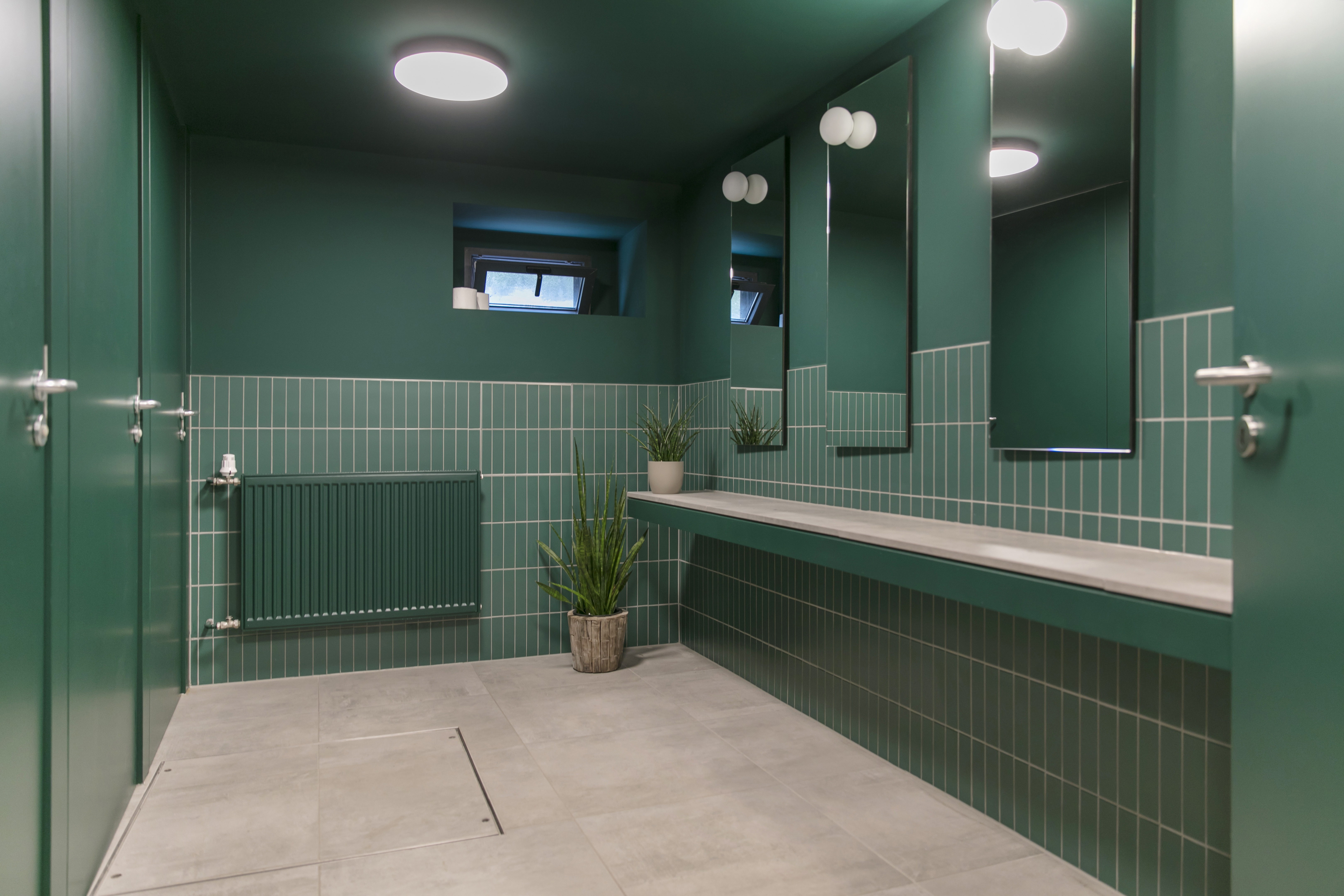 Stylish bathroom with green wall tiles and grey floor tiles.