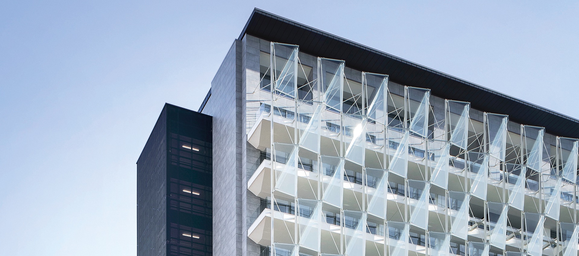 Modern building facade with striking triangular glass and structured elements.
