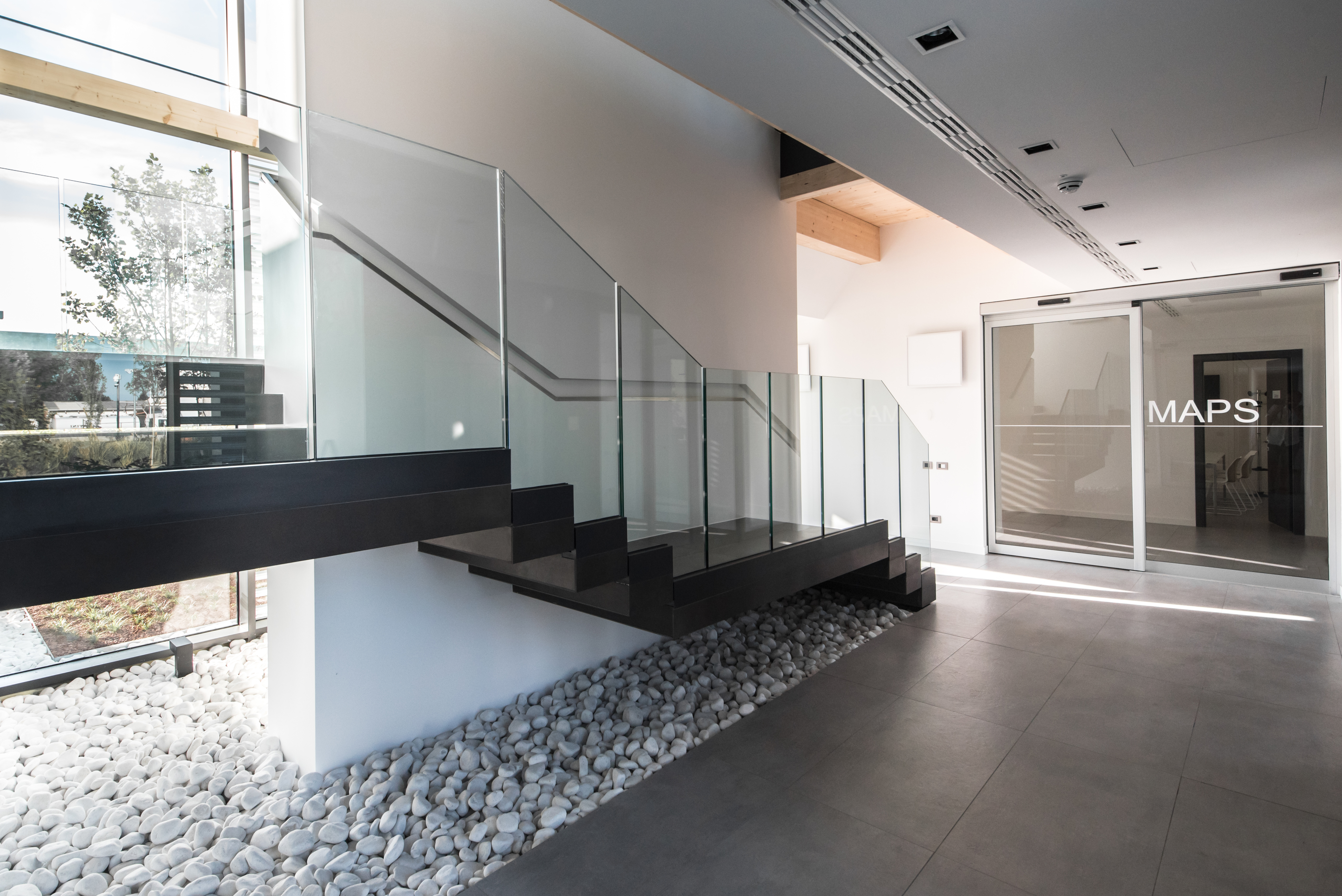 Modern interior with high-quality dark floor tiles and glass railing.