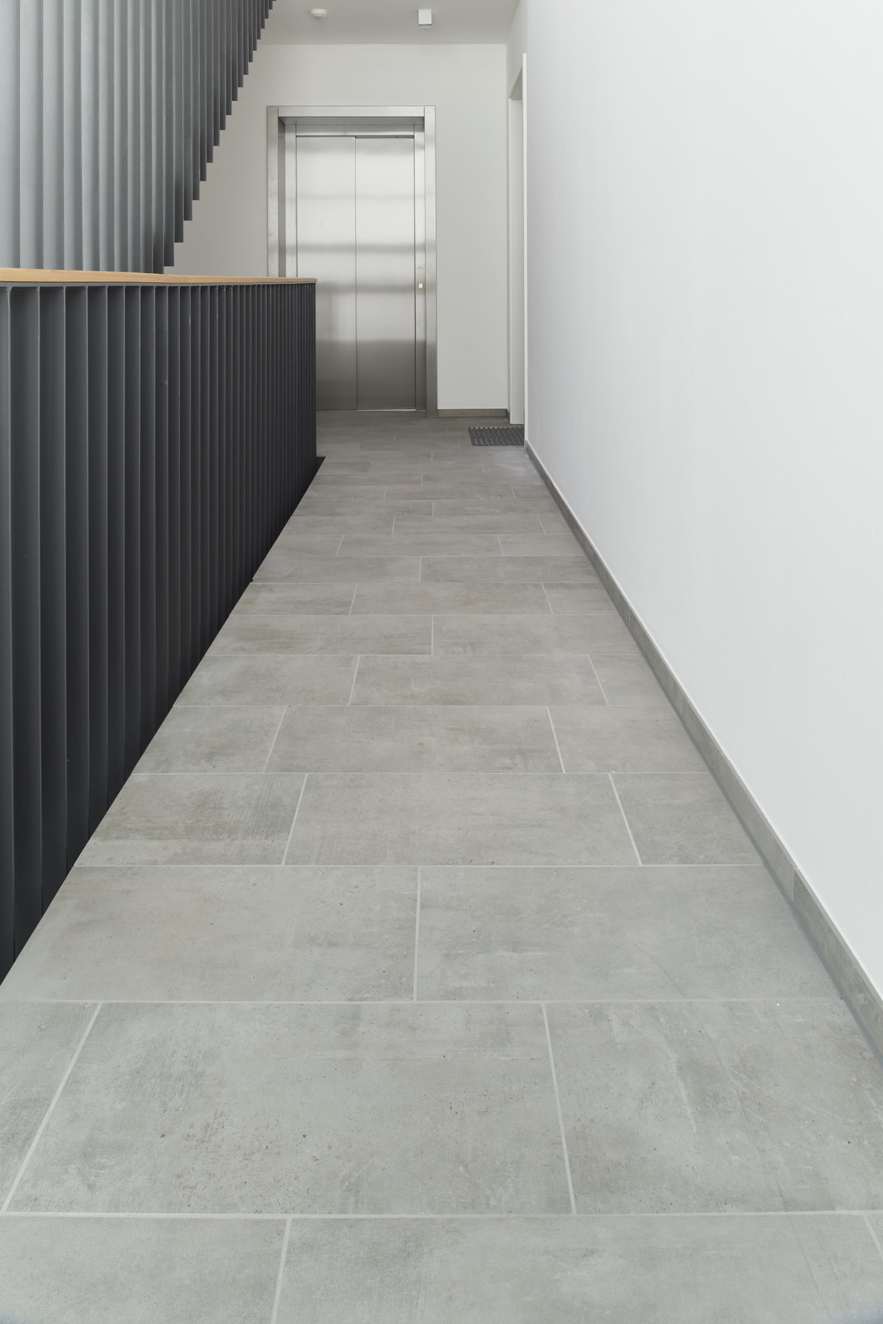 Modern large-format light grey indoor hallway tiles.